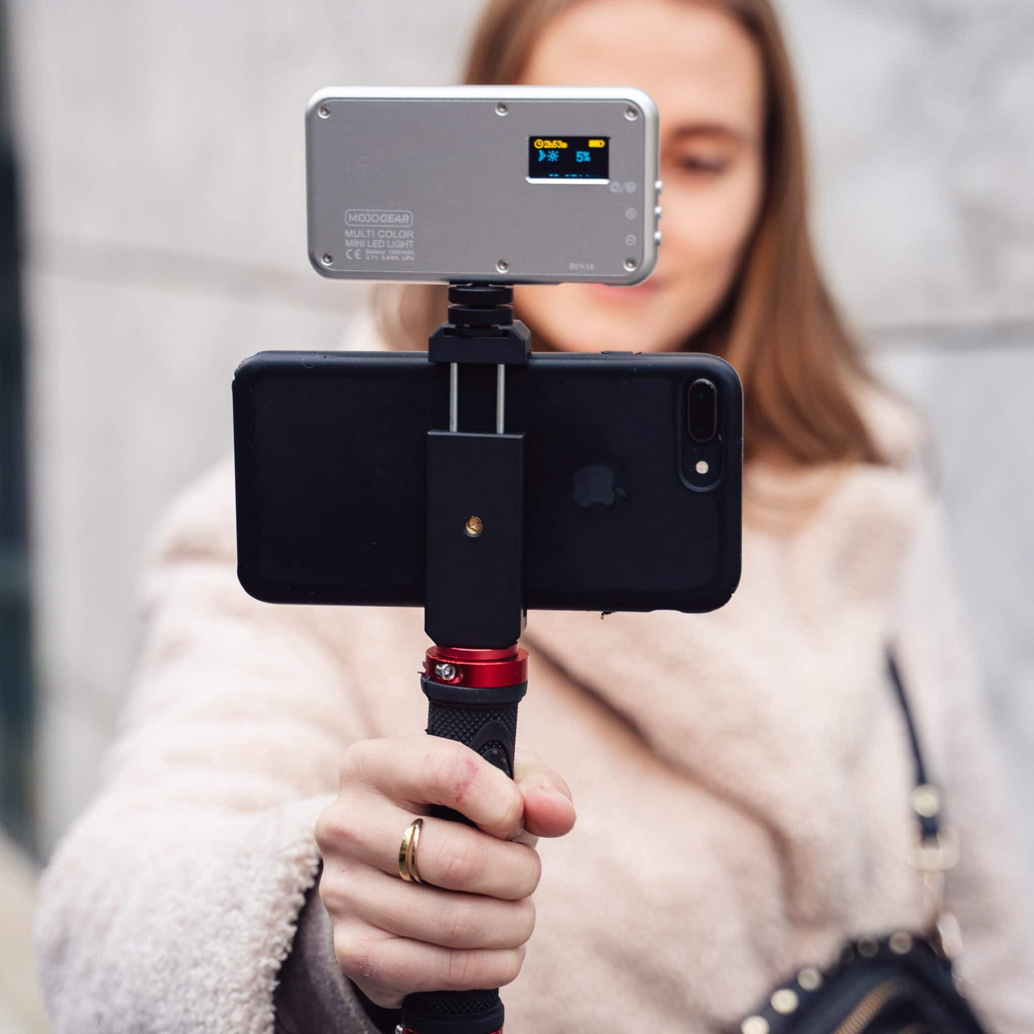Een vrouw die een telefoon vasthoudt met een klein lampje erop. Het lampje heeft een scherm dat instellingen toont.