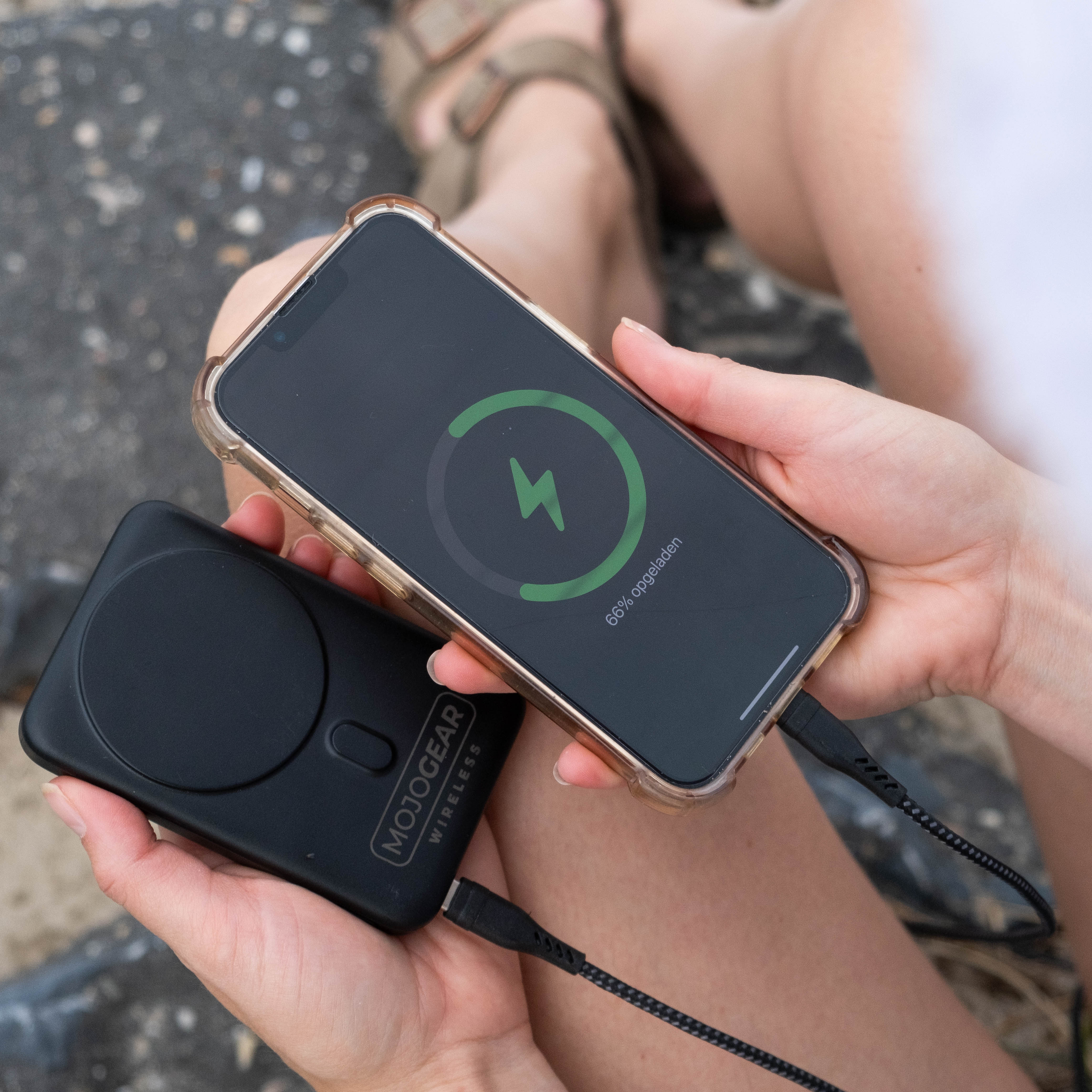 Zwarte telefoon draadloos opladen. Powerbank aangesloten. Scherm toont laadstatus.