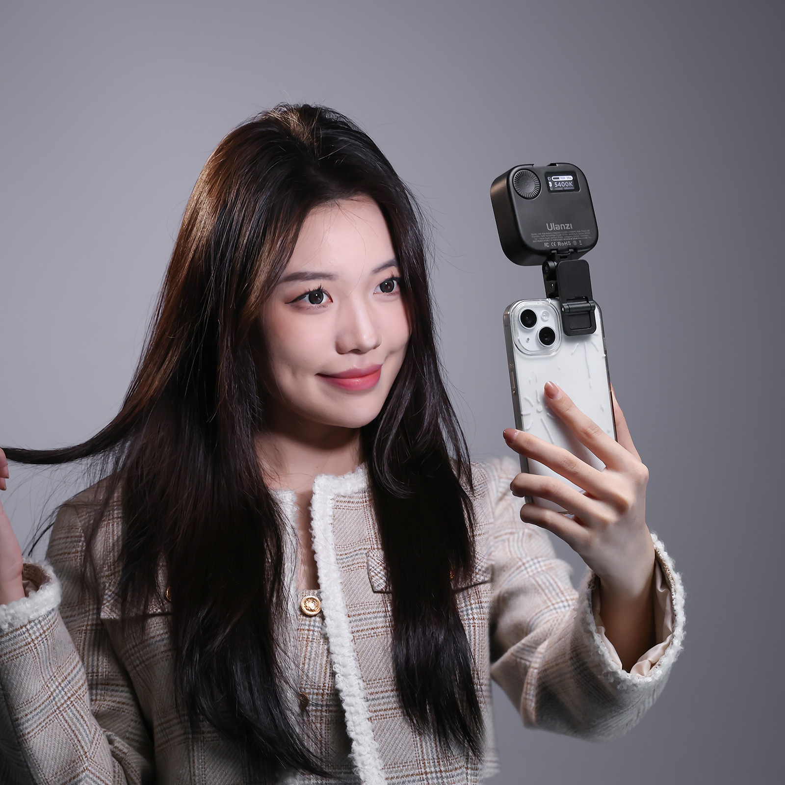 Kobieta trzyma telefon z dołączoną lampą błyskową, uśmiechając się do telefonu.