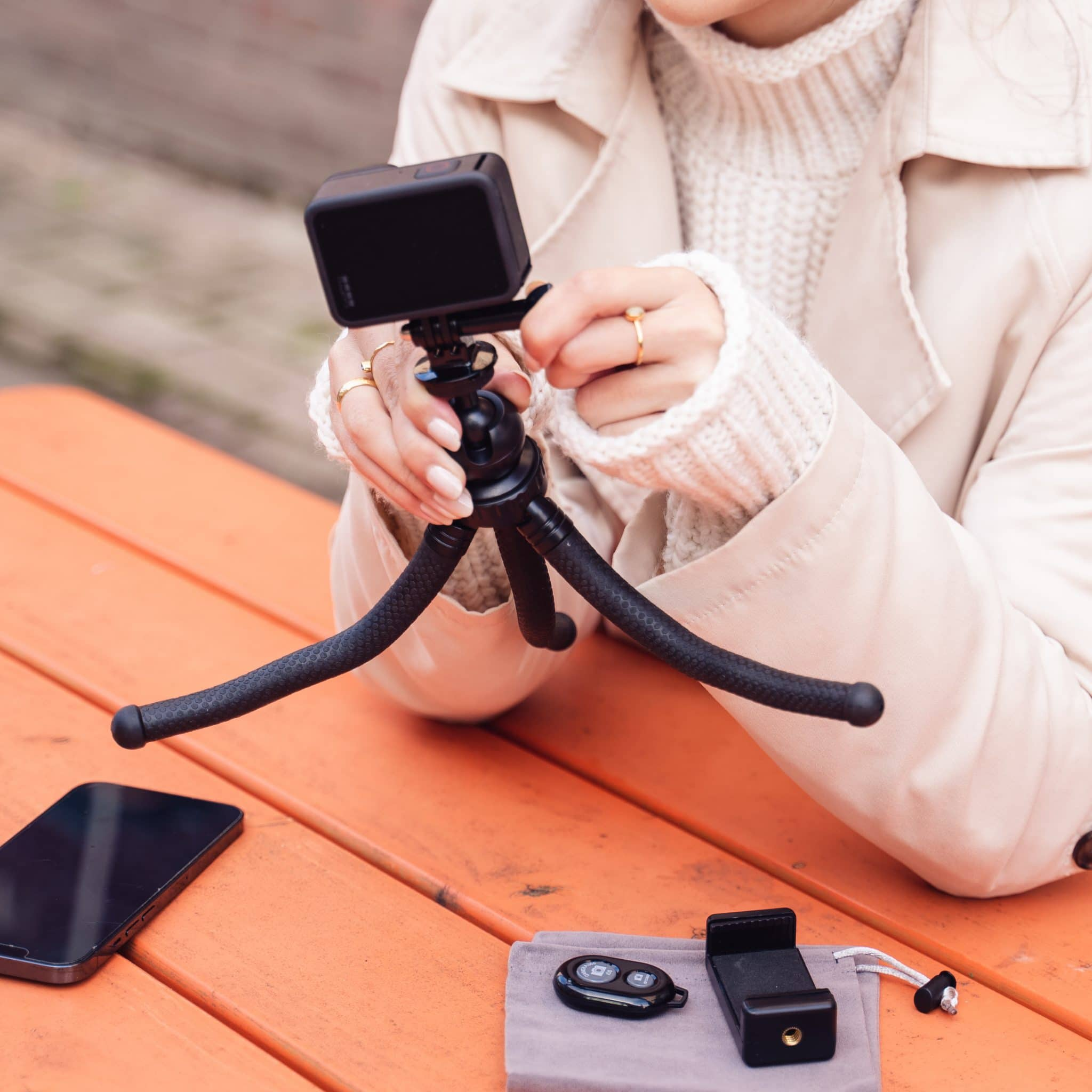 A person using a small tripod with a phone and a camera mounted on it.