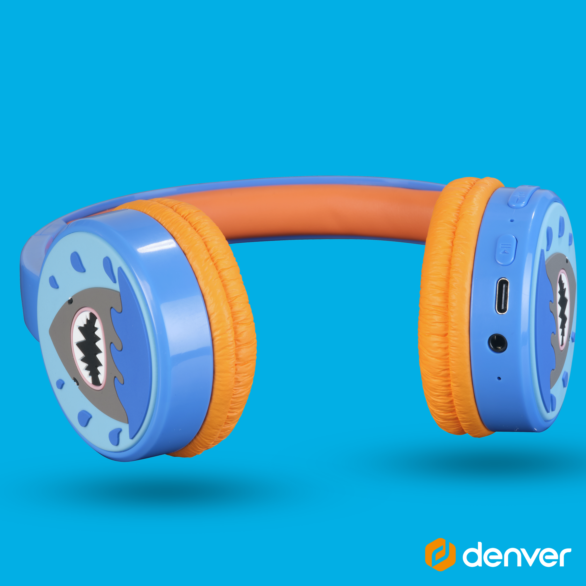 Niebieskie i pomarańczowe słuchawki z motywem rekina na nausznikach. Tło niebieskie.