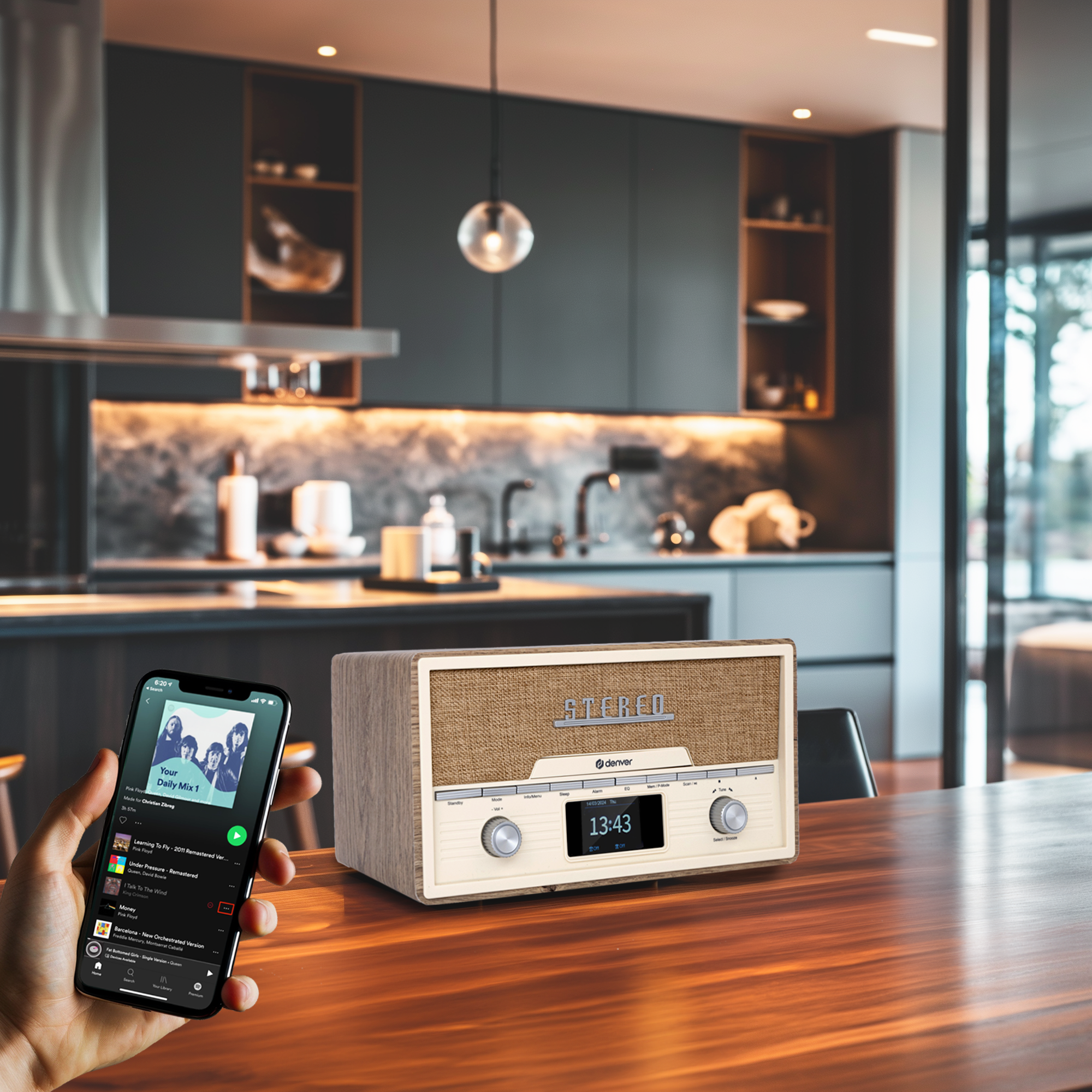 Ręka trzymająca telefon z muzyką obok retro stereo na stole w kuchni.