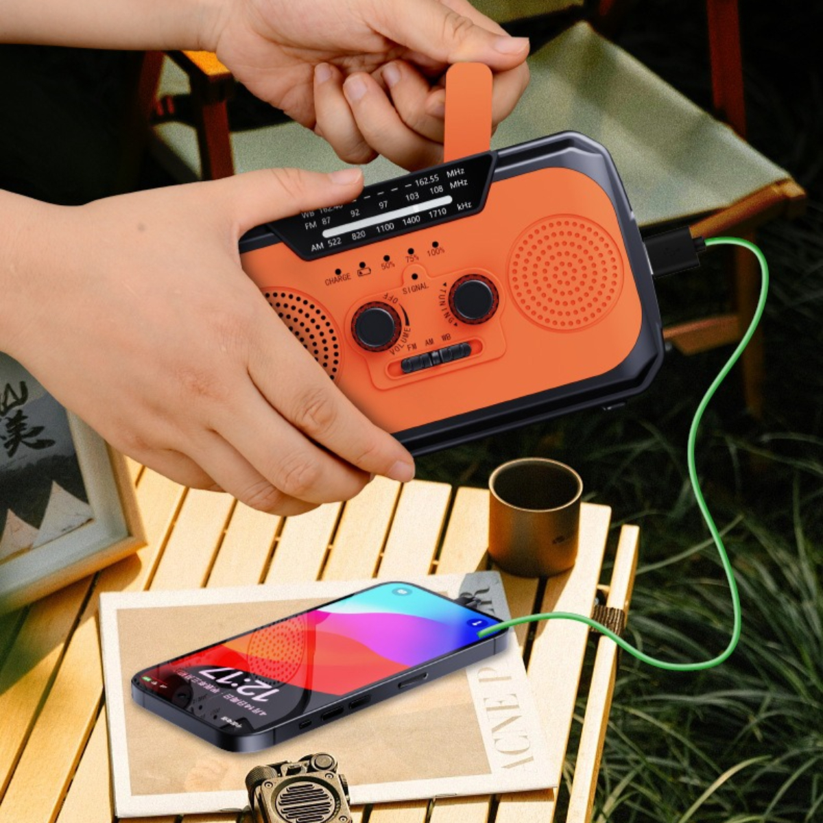 Hände halten ein orange-schwarzes Radio. Ein Telefon wird geladen und eine Tasse steht auf einem Tisch.