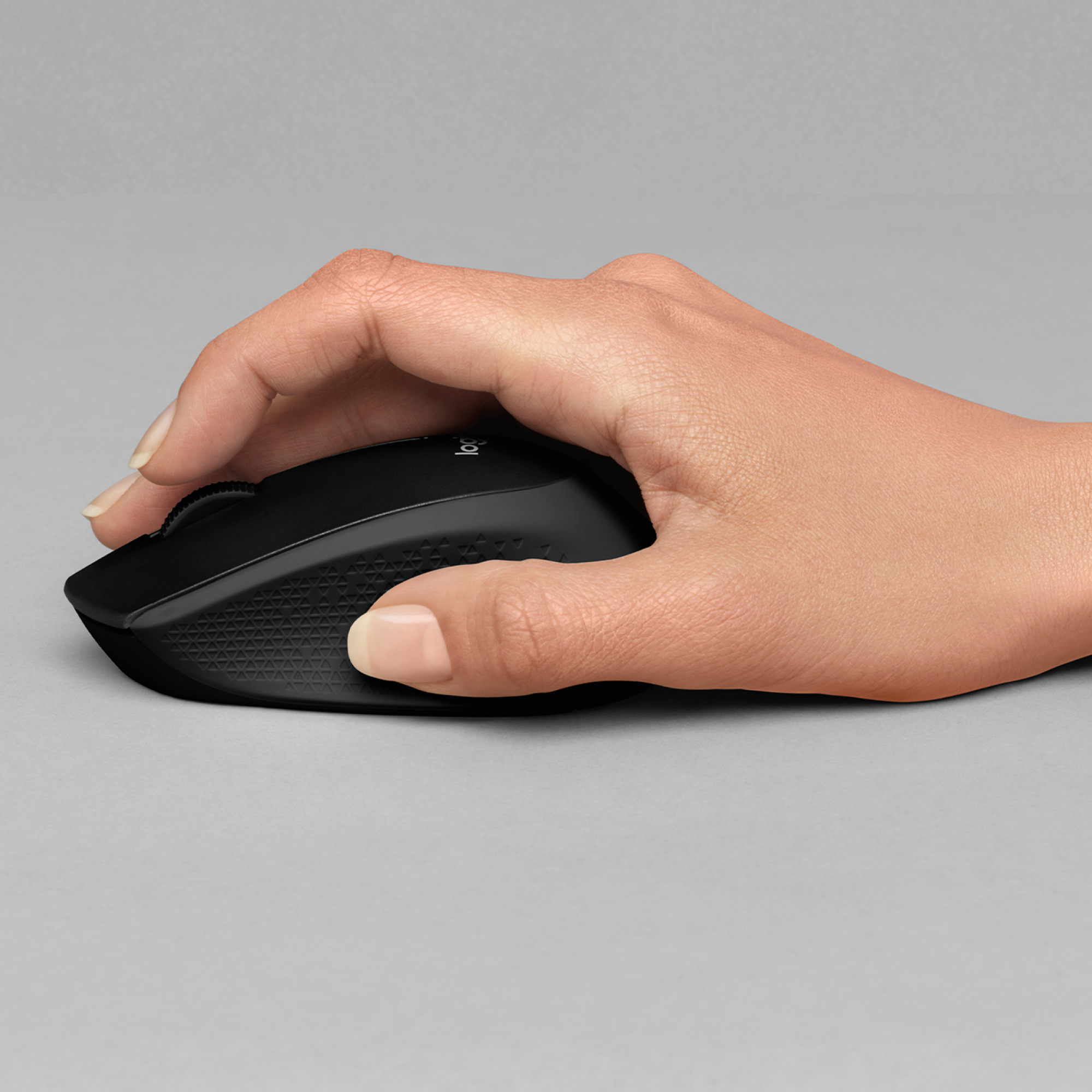 Een hand houdt een zwarte muis vast. De muis heeft een scrollwiel en een getextureerde zijkant.