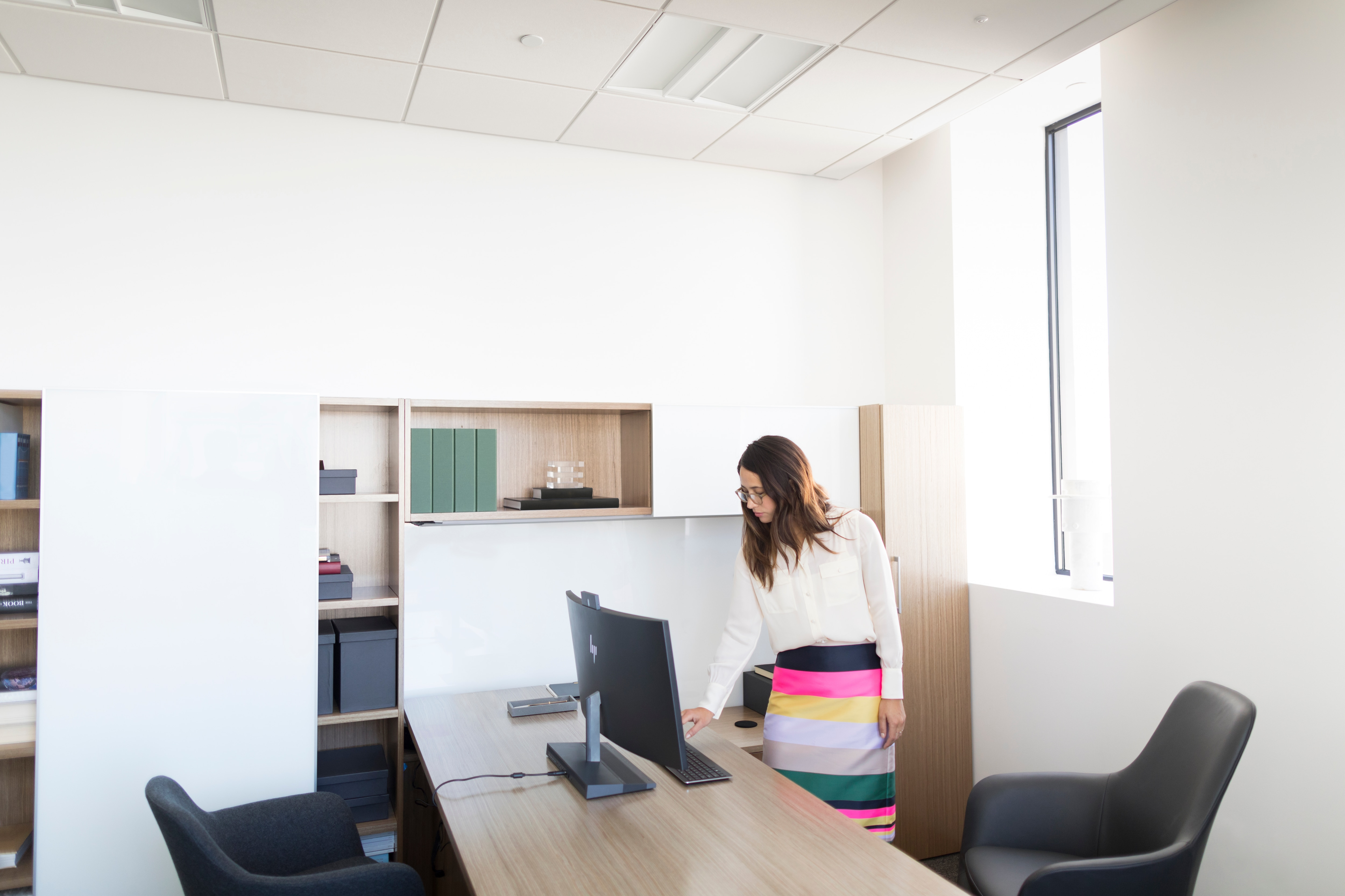 Kobieta w biurze stoi przy biurku z komputerem.