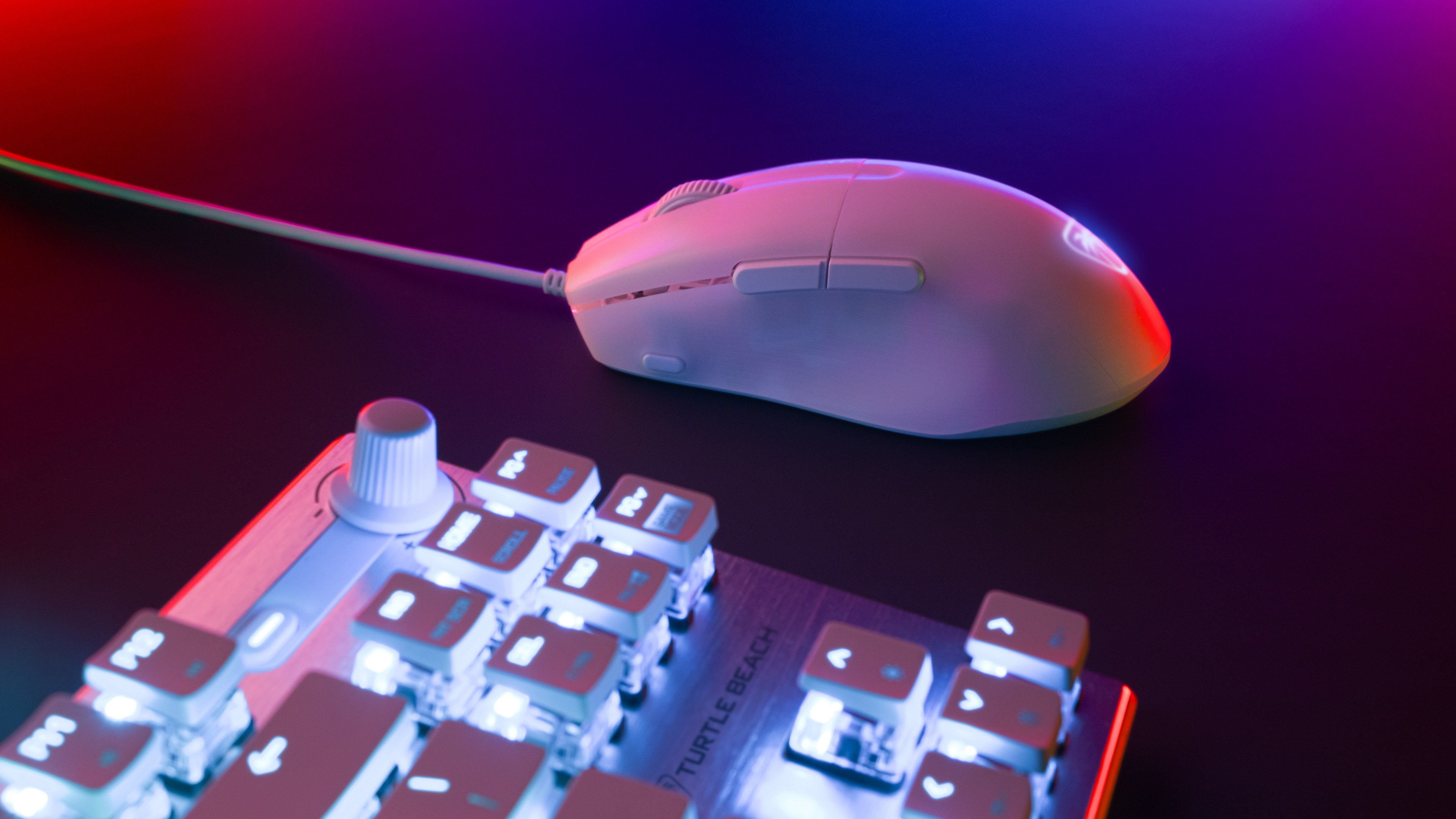 Weiße Gaming-Maus und -Tastatur mit farbenfroher Beleuchtung. Die Maus befindet sich auf einer schwarzen Oberfläche.