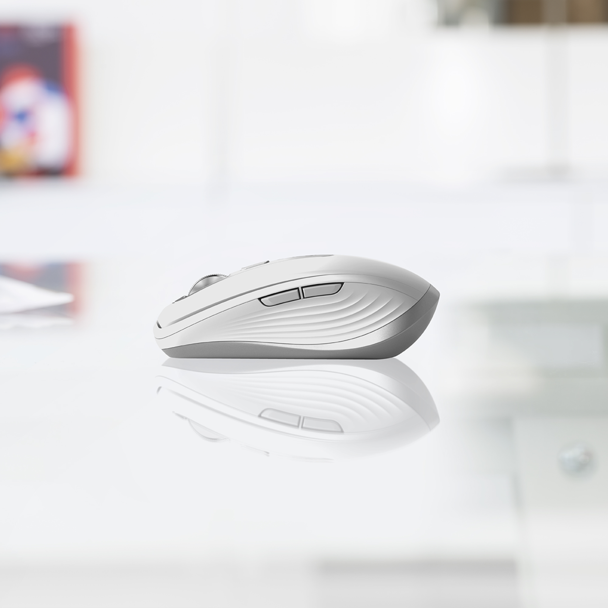 Un ratón inalámbrico blanco sobre una superficie brillante. El ratón tiene un diseño elegante y ergonómico.