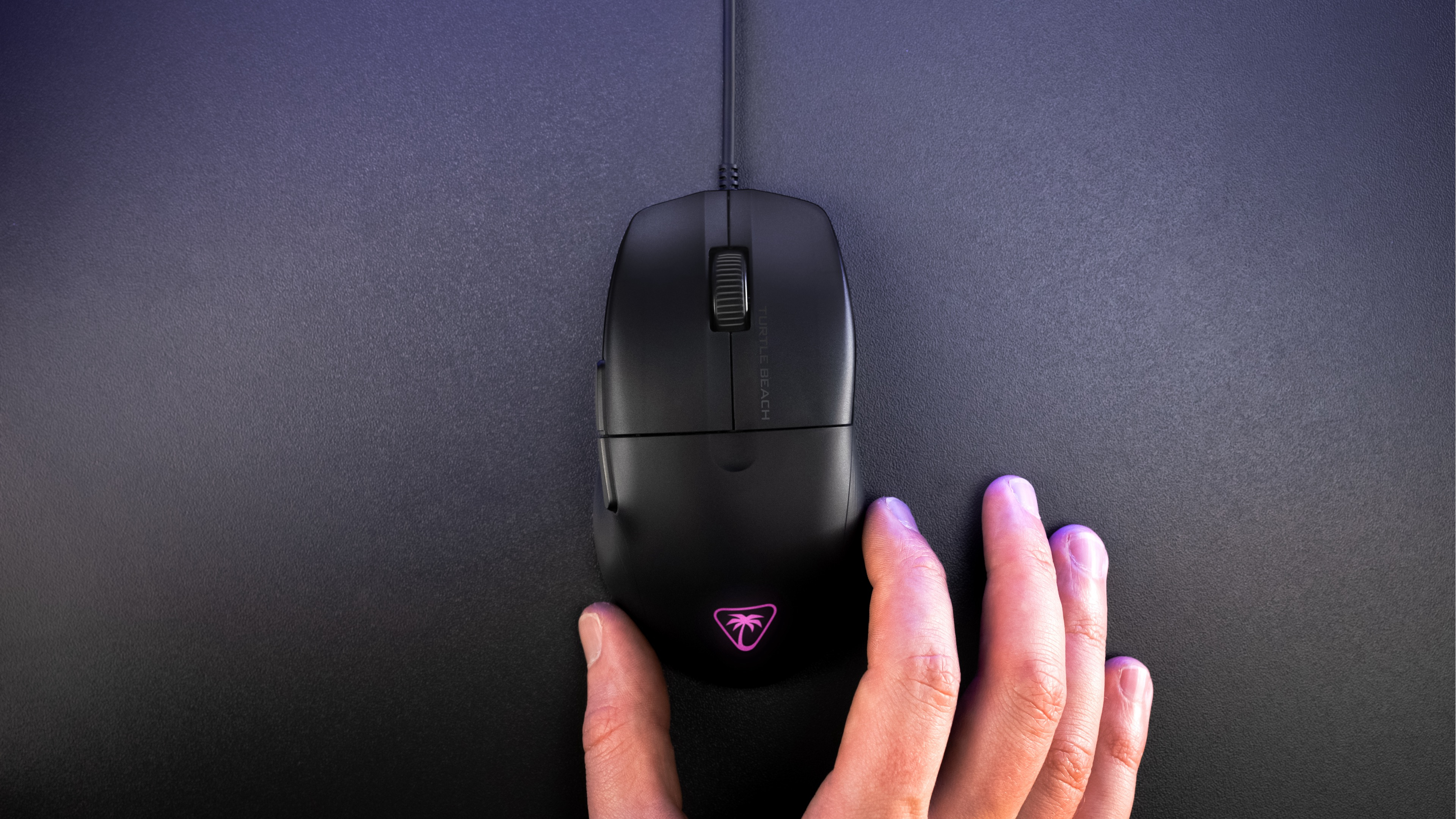Black gaming mouse on a black surface. A hand is touching the mouse.