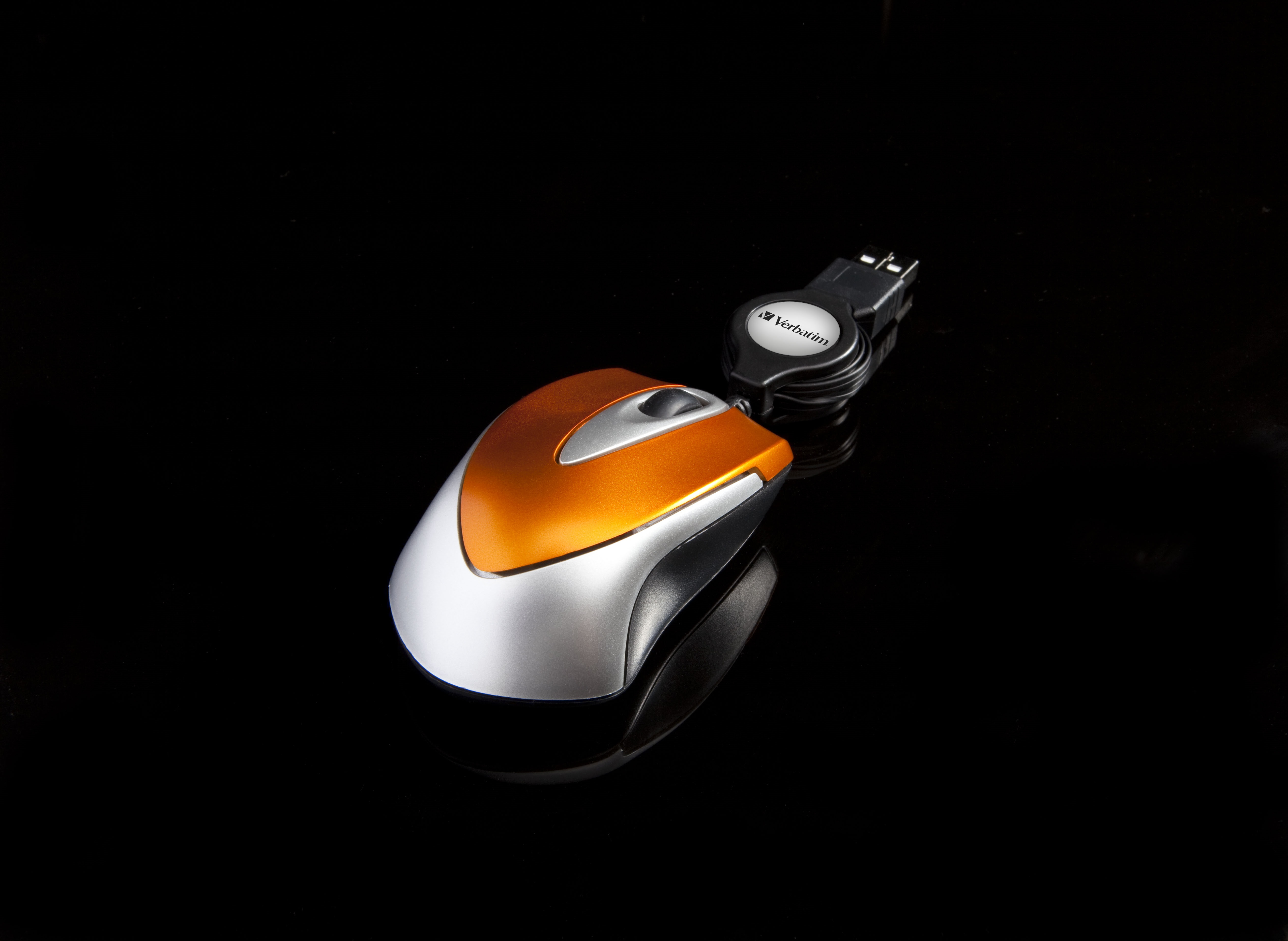 Orange and silver wireless computer mouse on a black surface with a black cord.