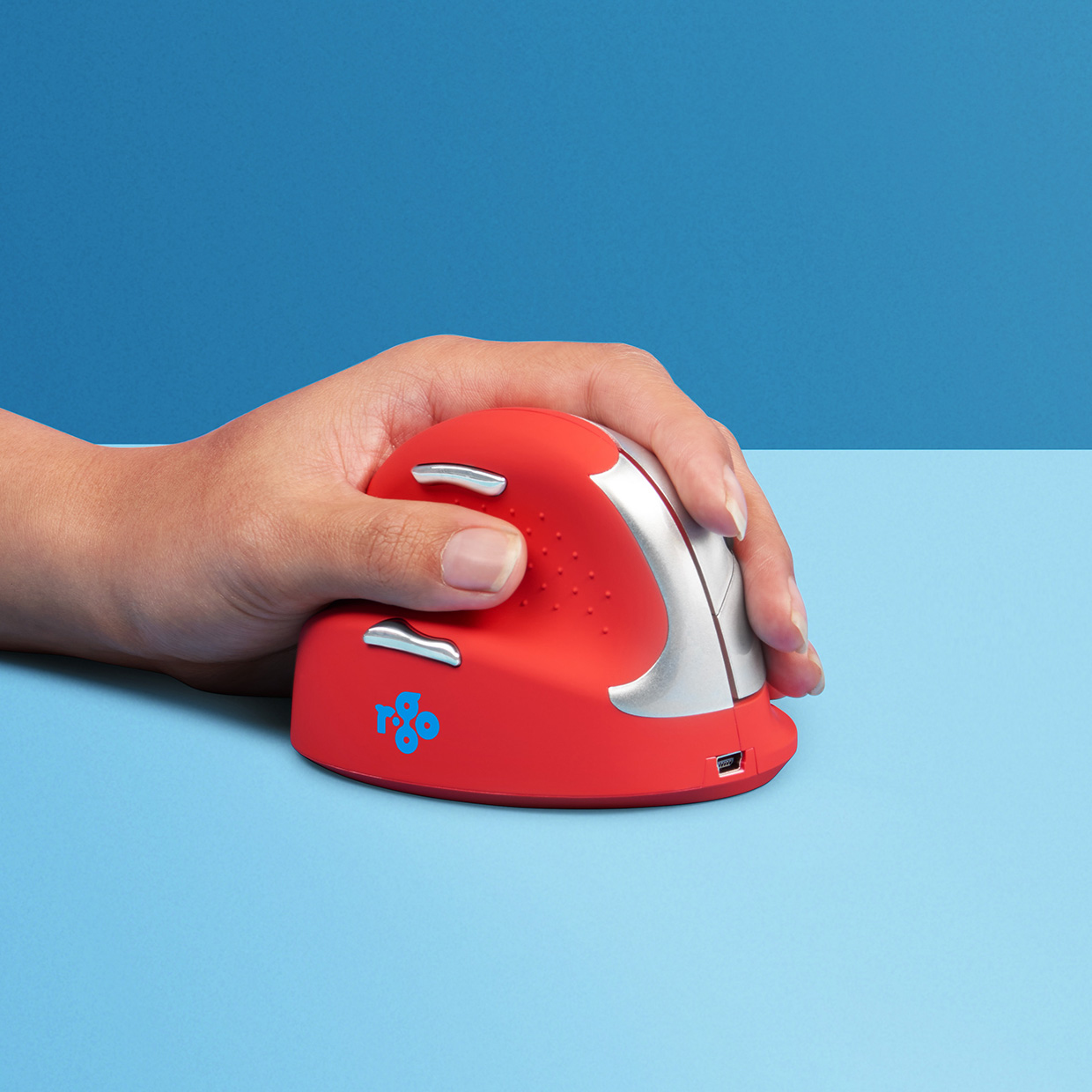 Un ratón ergonómico rojo sostenido por una mano, con un fondo azul.