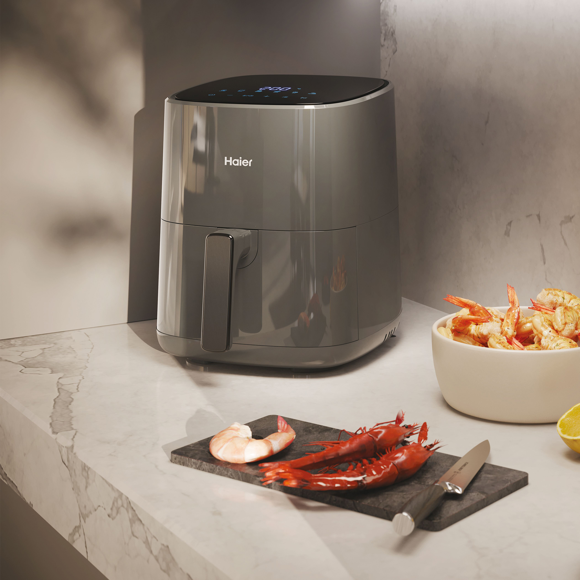 Frytkownica powietrzna z daniem z krewetek na blacie. W pobliżu nóż i cytryna.