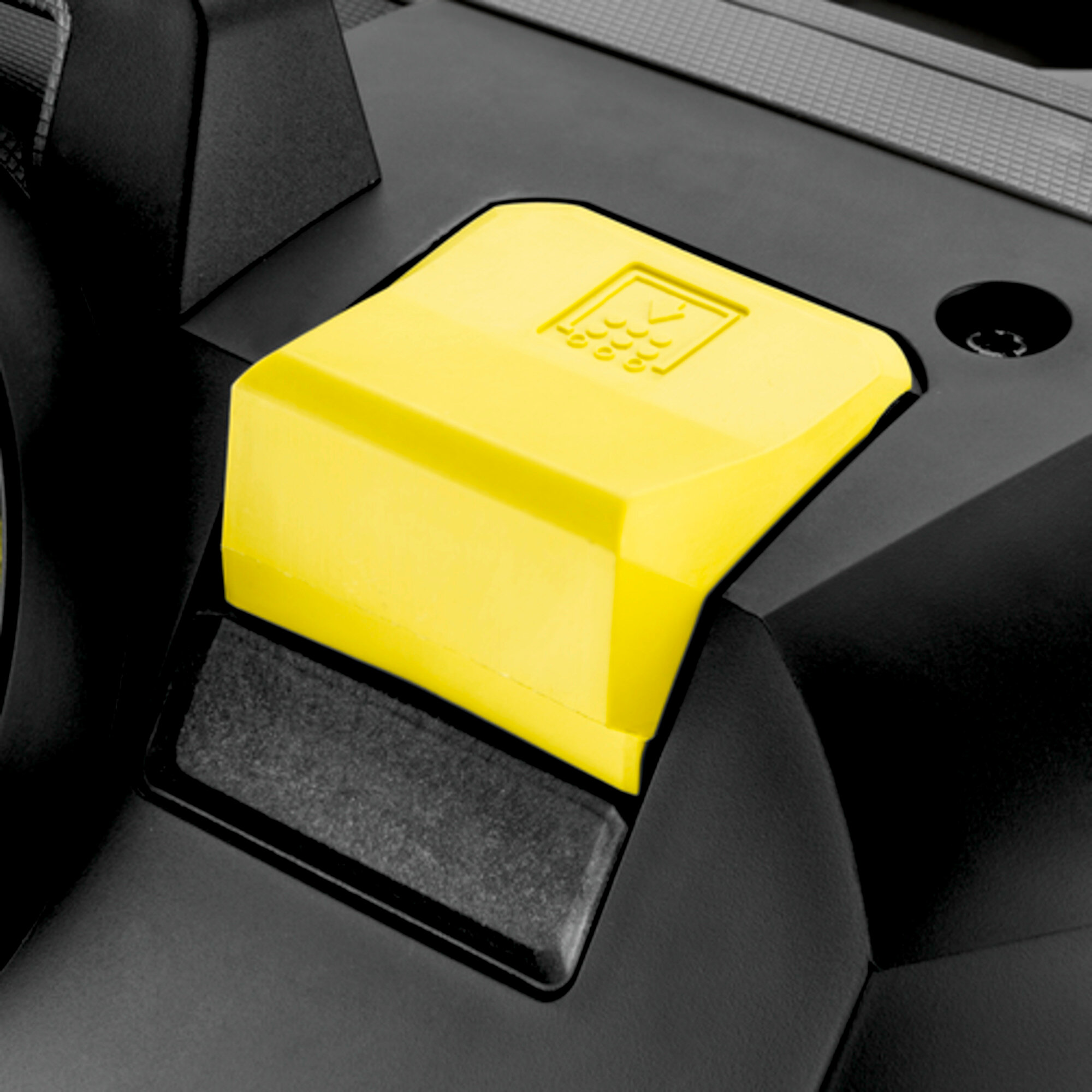 Zbliżenie żółtego przycisku na czarnym odkurzaczu. Przycisk jest prostokątny.