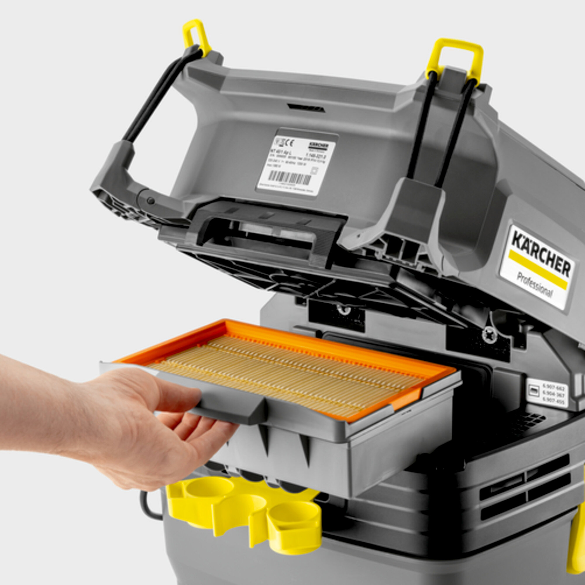 Zbliżenie dłoni wyjmującej filtr z szarego odkurzacza Kärcher.