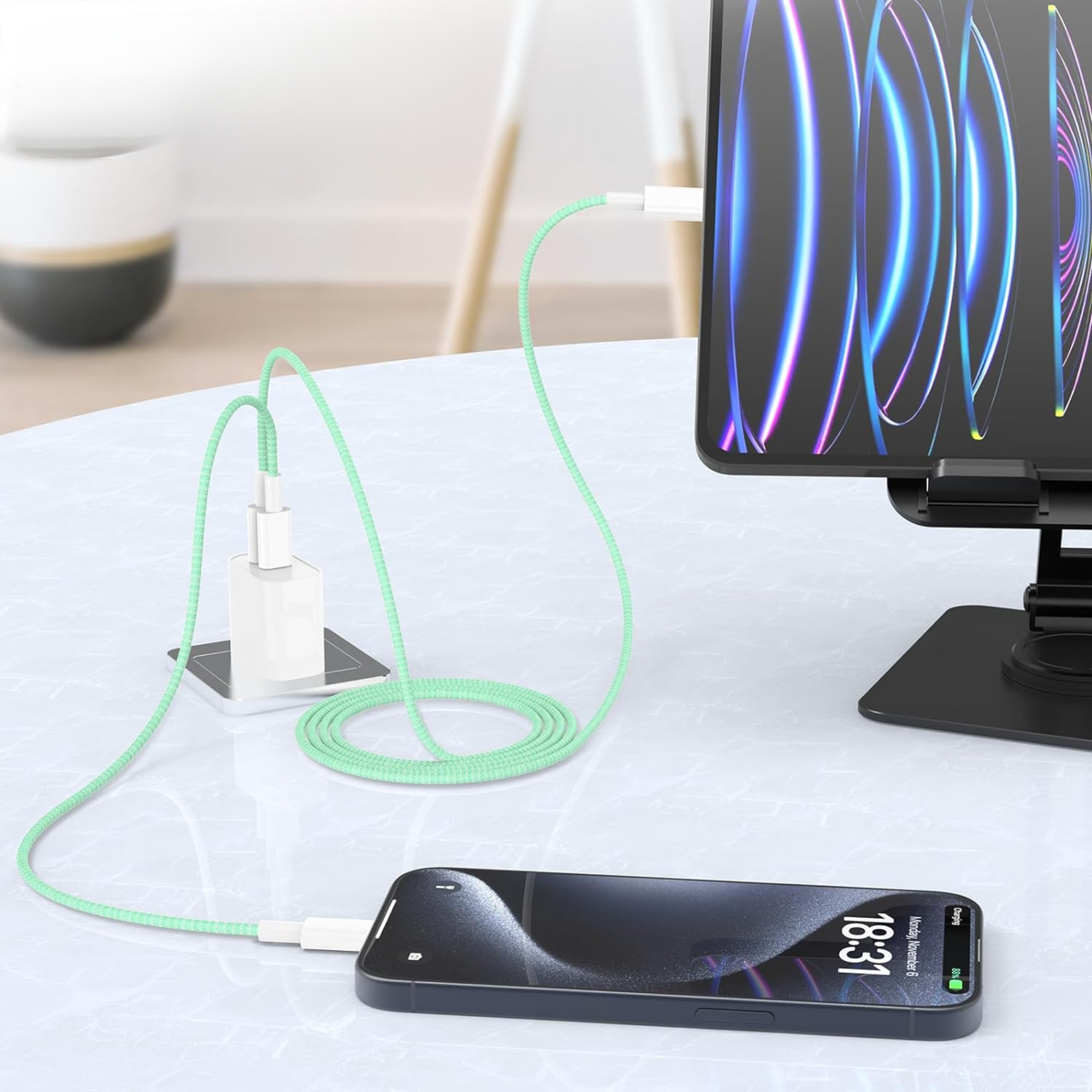 Il telefono sta caricando un tablet con un cavo verde su un tavolo bianco. Il tablet mostra una grafica colorata.