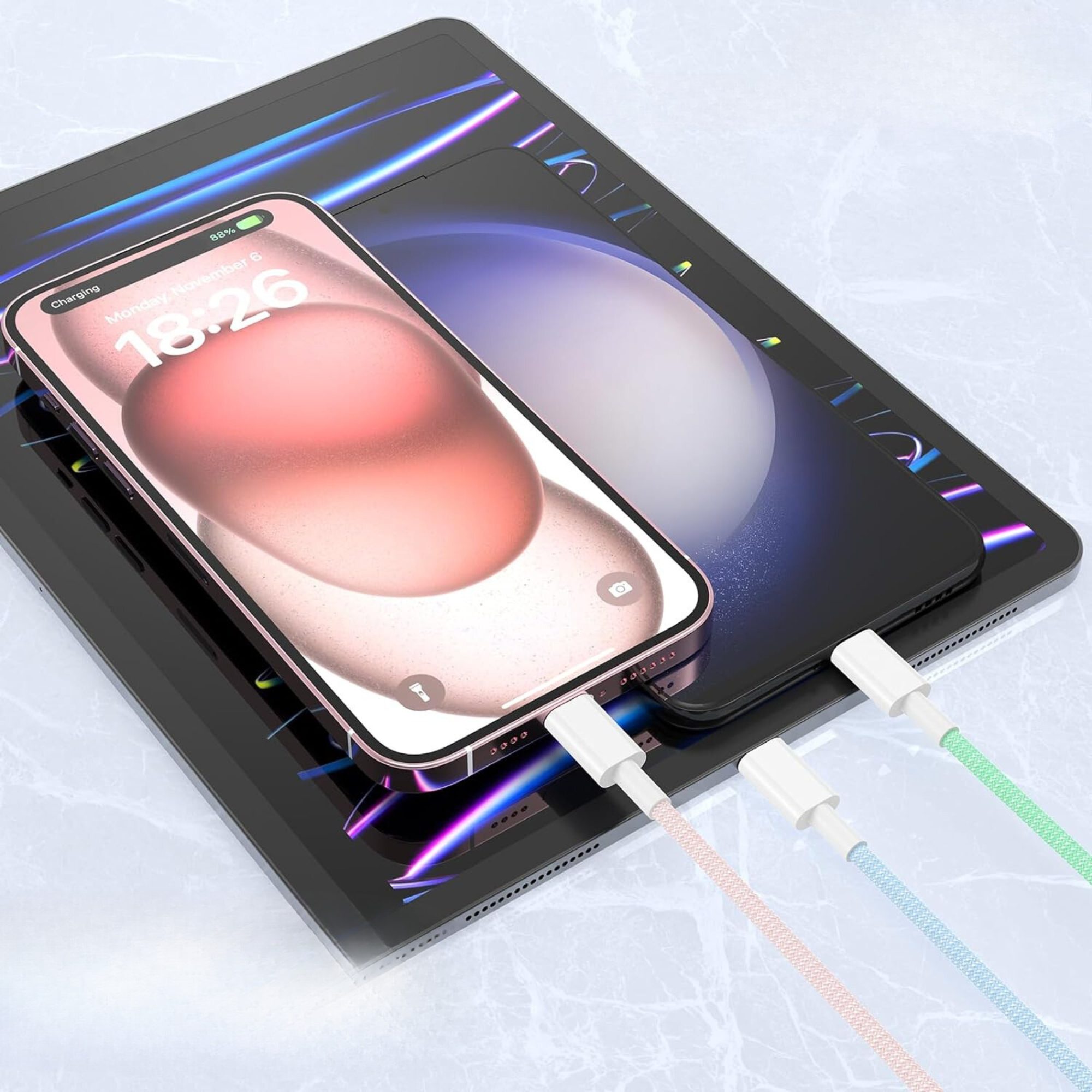 Telefono e tablet in carica con più cavi. Cavi rosa, blu e verdi collegati. Superficie lucida.
