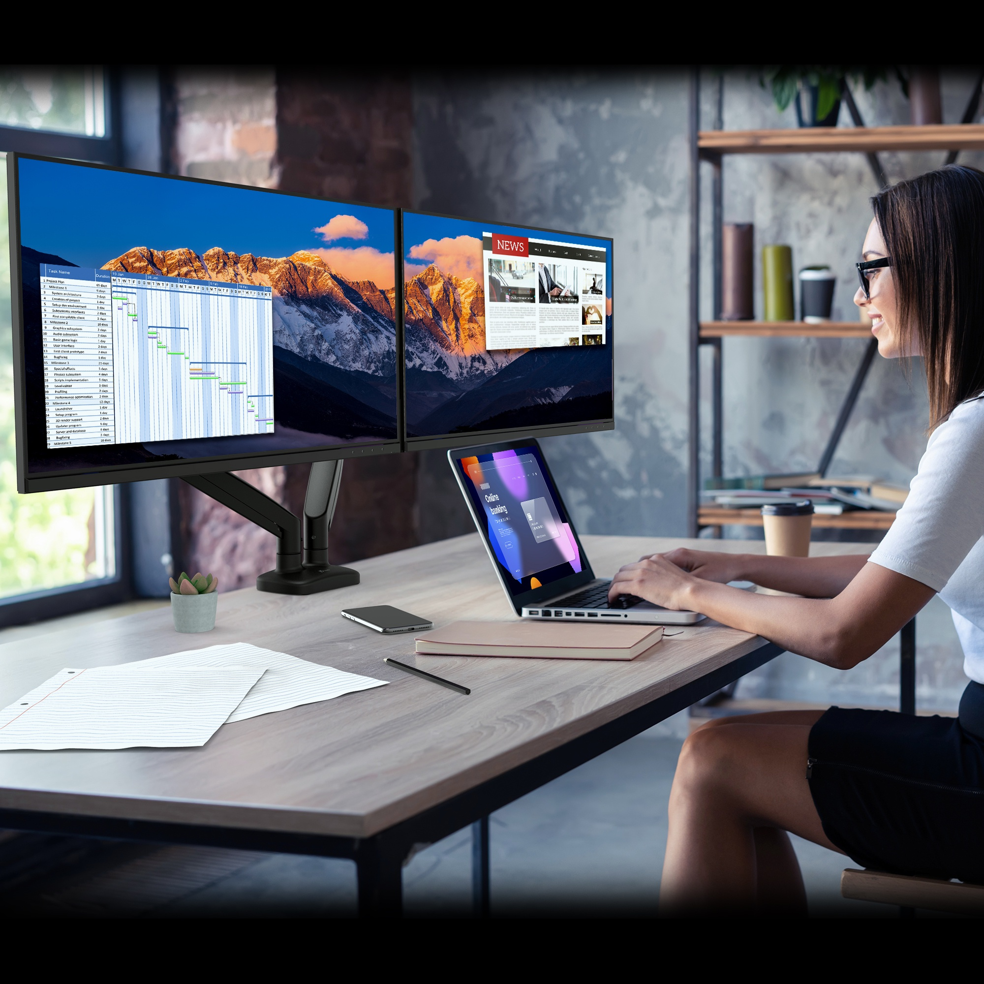 Une femme utilise un ordinateur portable et deux moniteurs sur un bureau dans un bureau.