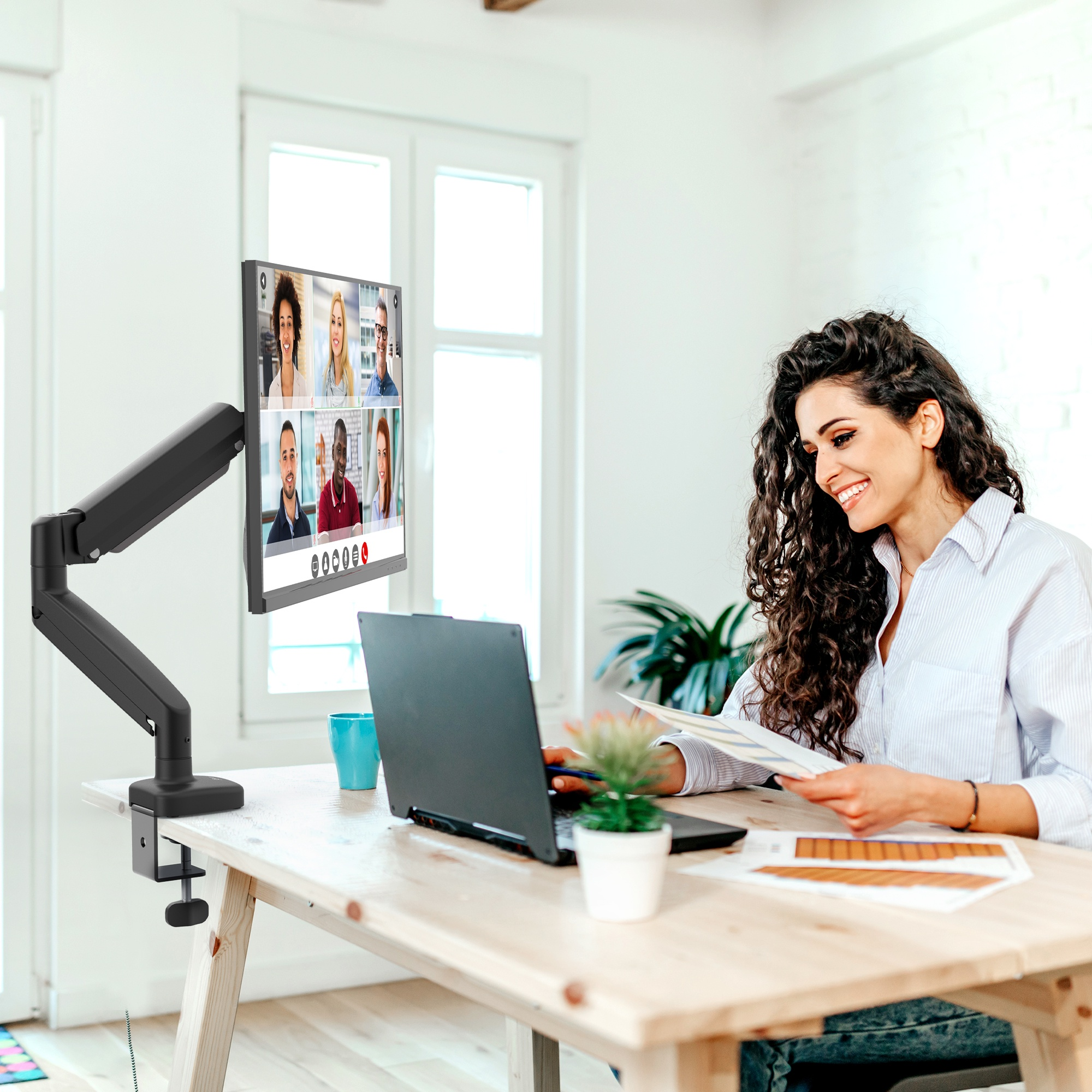 Une femme utilise un ordinateur portable connecté à un support d'écran, avec un appel vidéo.