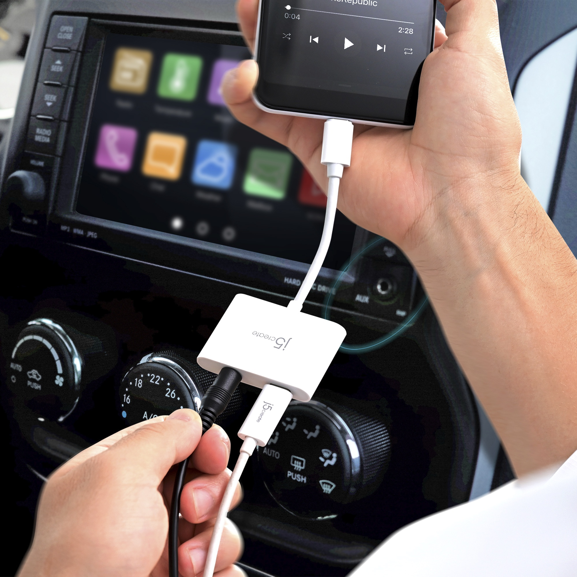 Una mano sostiene un teléfono conectado a un adaptador blanco. Otra mano enchufa cables al adaptador.