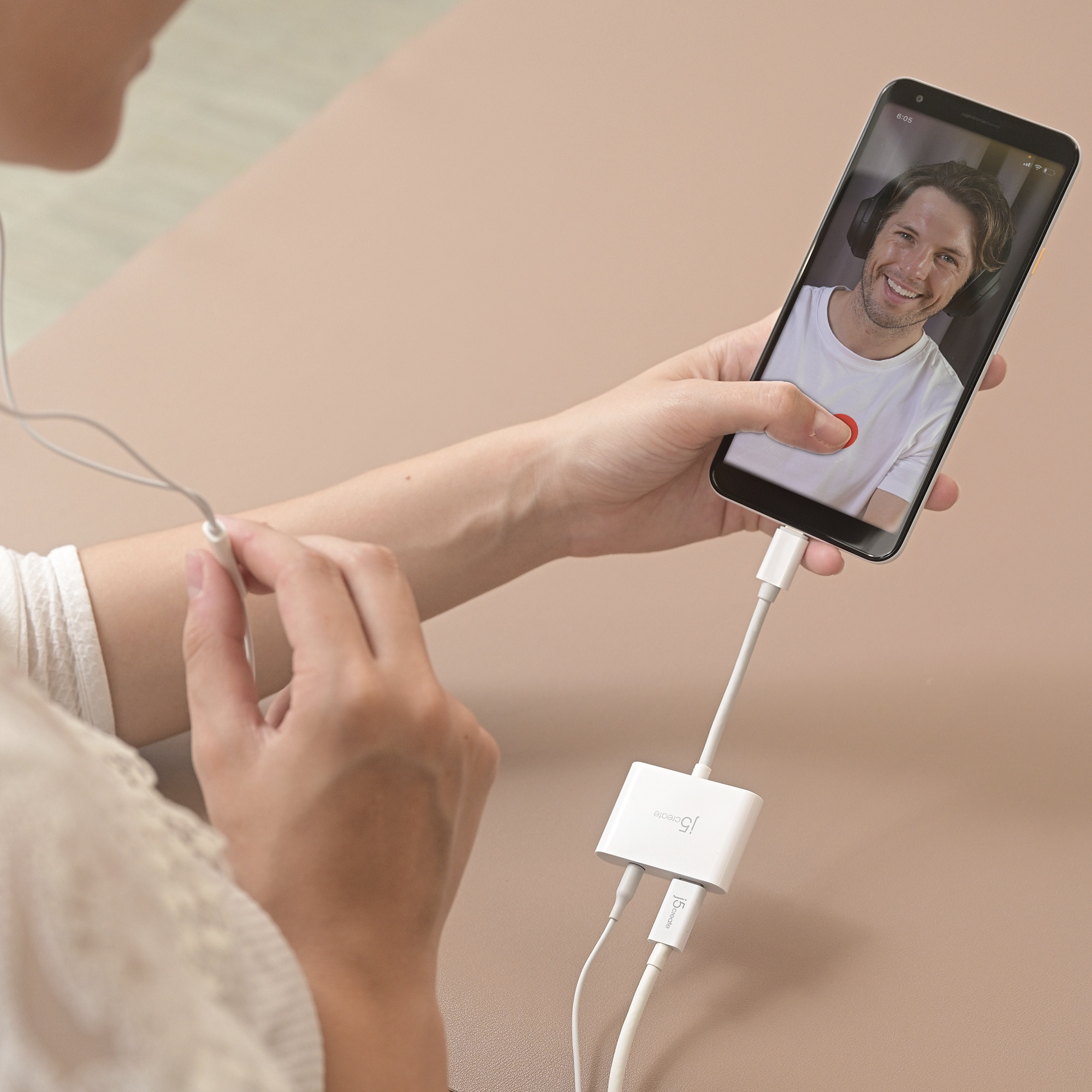 Mujer en videollamada. Teléfono conectado por adaptador. Hombre sonriendo en pantalla.