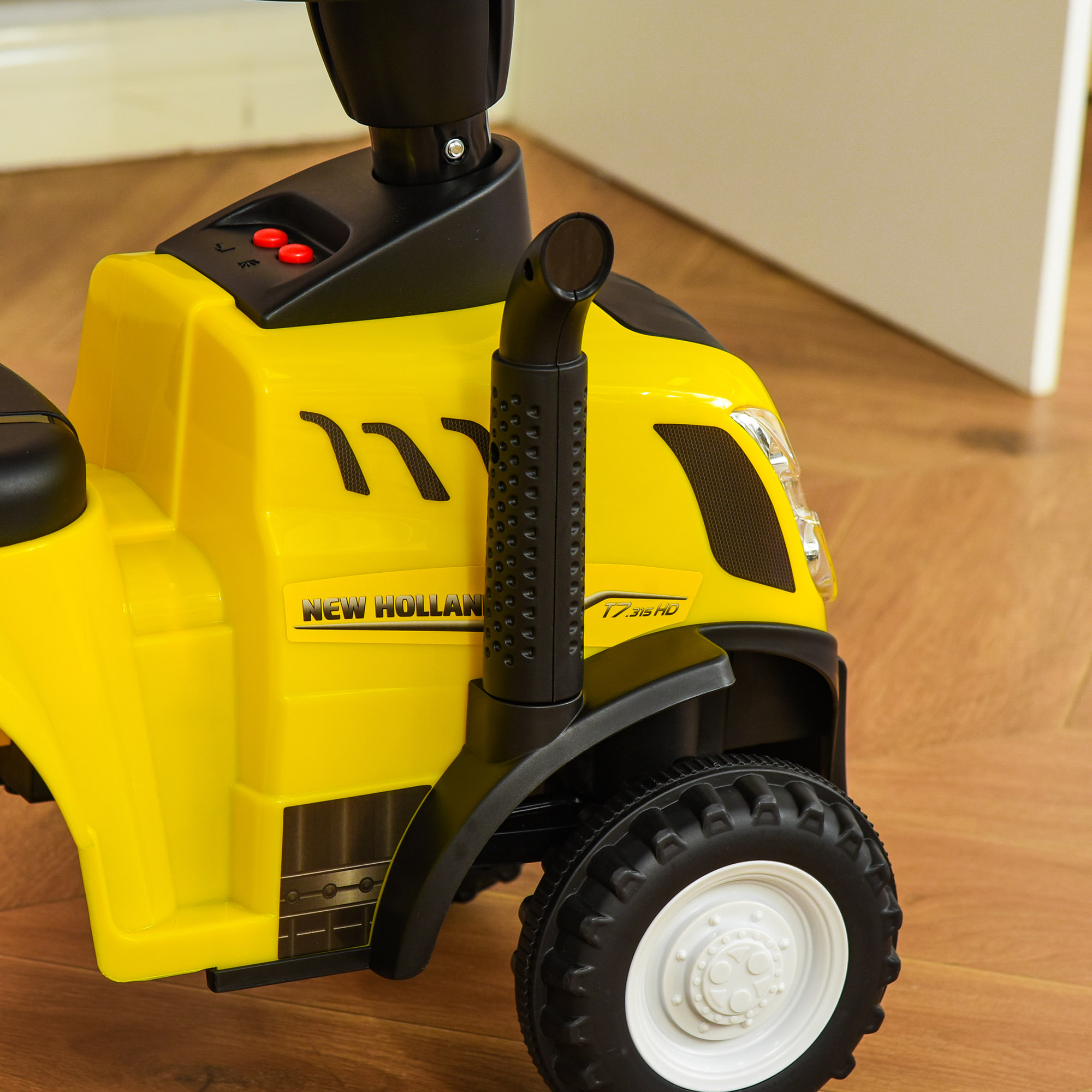 Tractor de juguete amarillo y negro con tubo de escape negro. Logotipo New Holland.