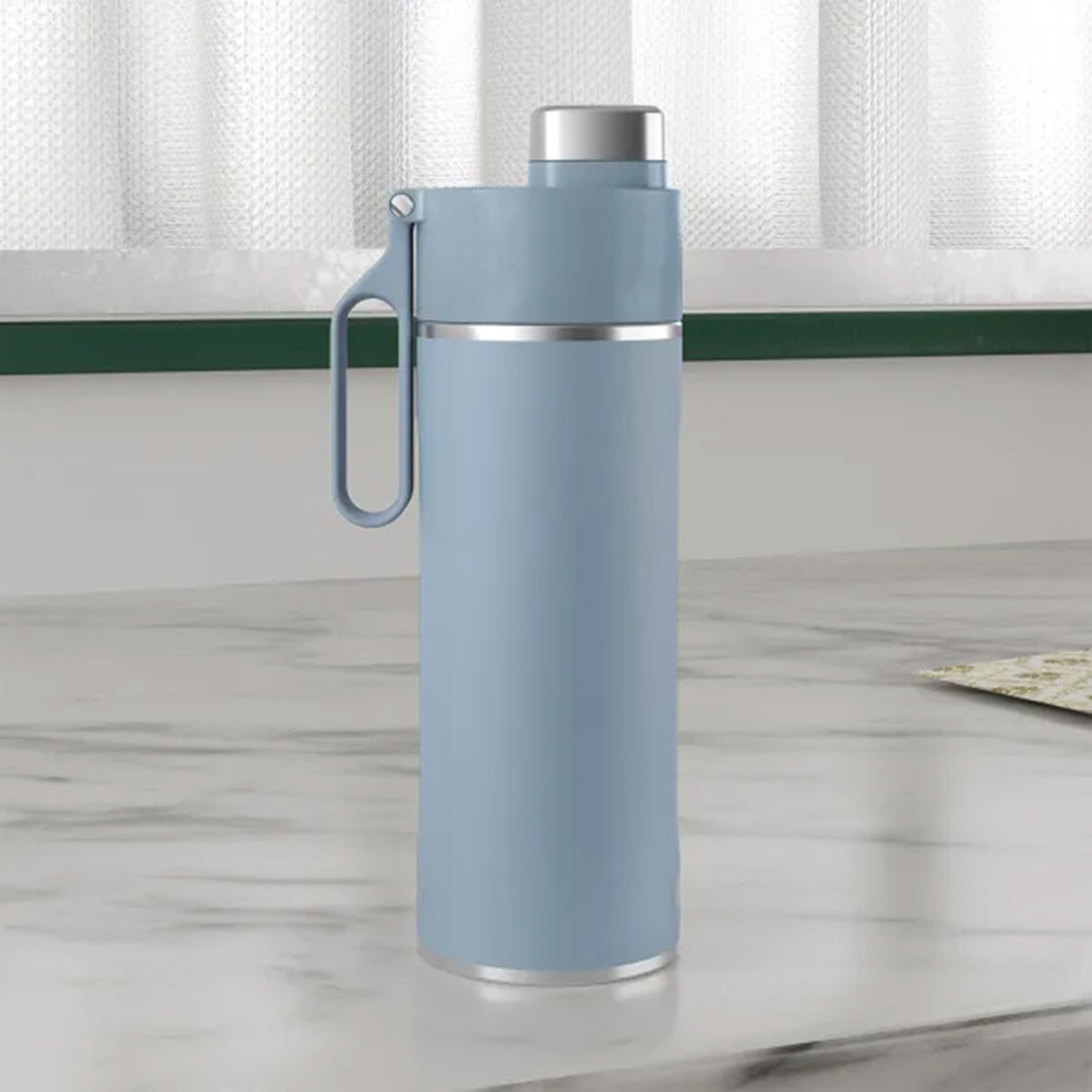 Blaue, isolierte Wasserflasche mit silbernem Deckel und Griff, auf Marmoroberfläche.
