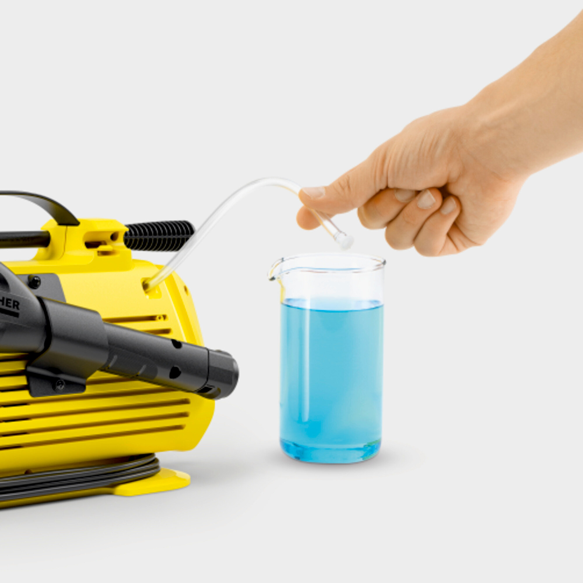 Unità gialla di idropulitrice con un tubo che si immerge in un bicchiere di liquido blu.