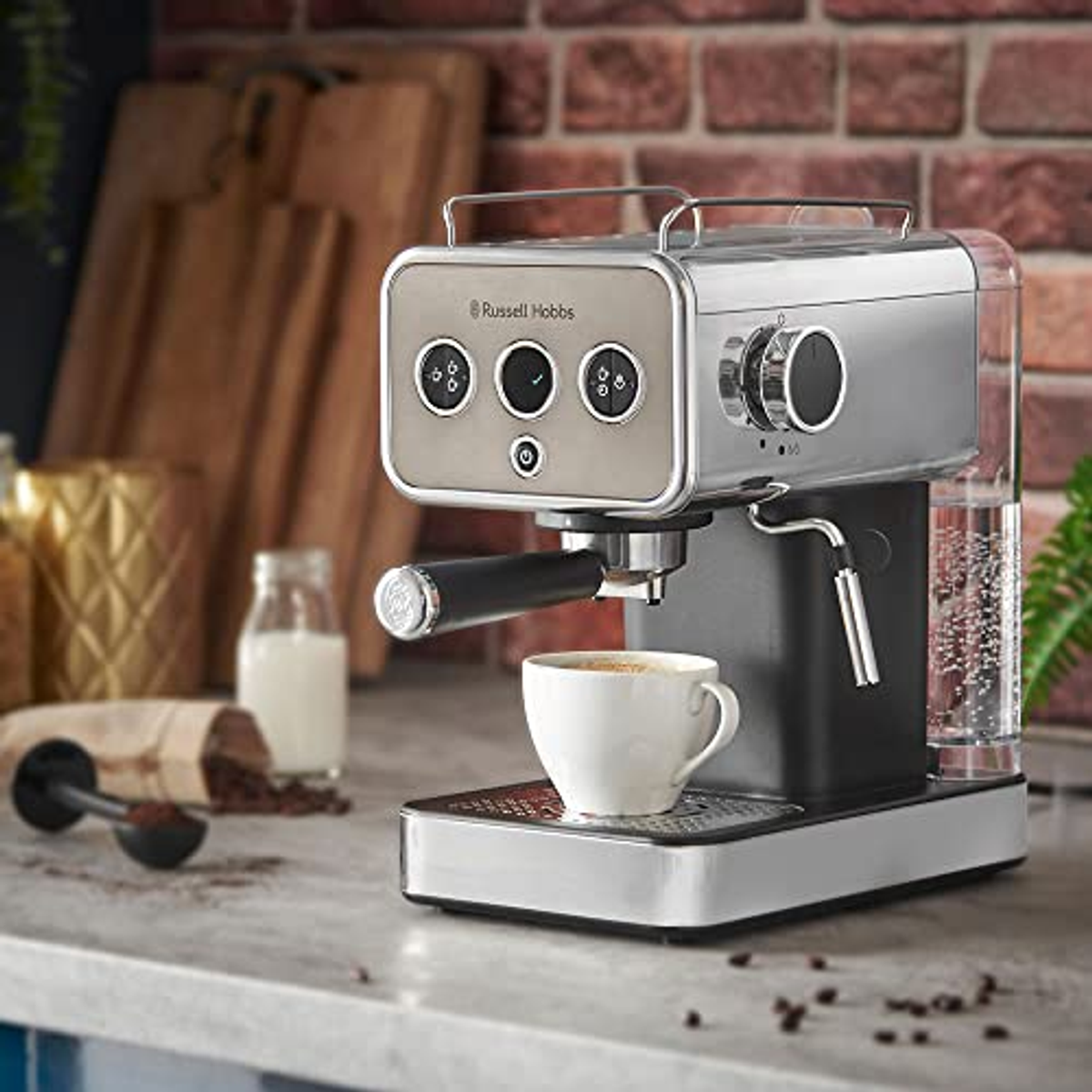Espressomaschine auf der Arbeitsplatte mit einer Tasse Kaffee. Eine Milchflasche und Kaffeebohnen sind vorhanden.