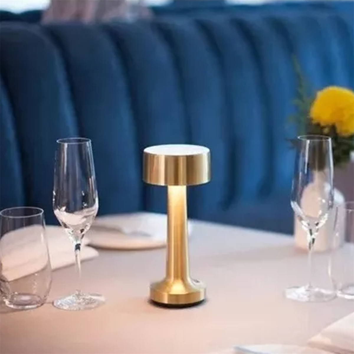 Goldene Tischlampe mit zwei Gläsern auf einem Tisch.