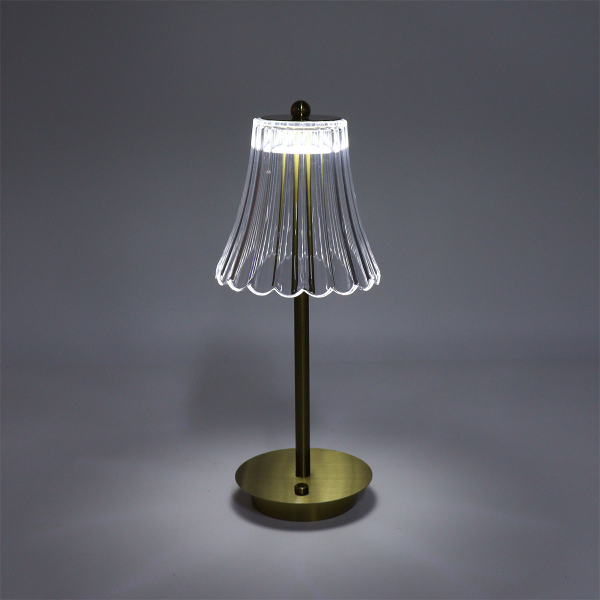 Goldene und transparente Lampe mit Sockel und Lampenschirm.