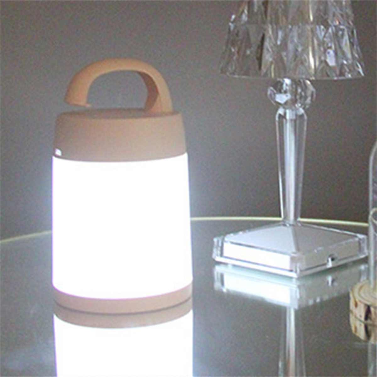 Eine weiß-beige Lampe mit Griff, hell leuchtend, und eine Kristalllampe.