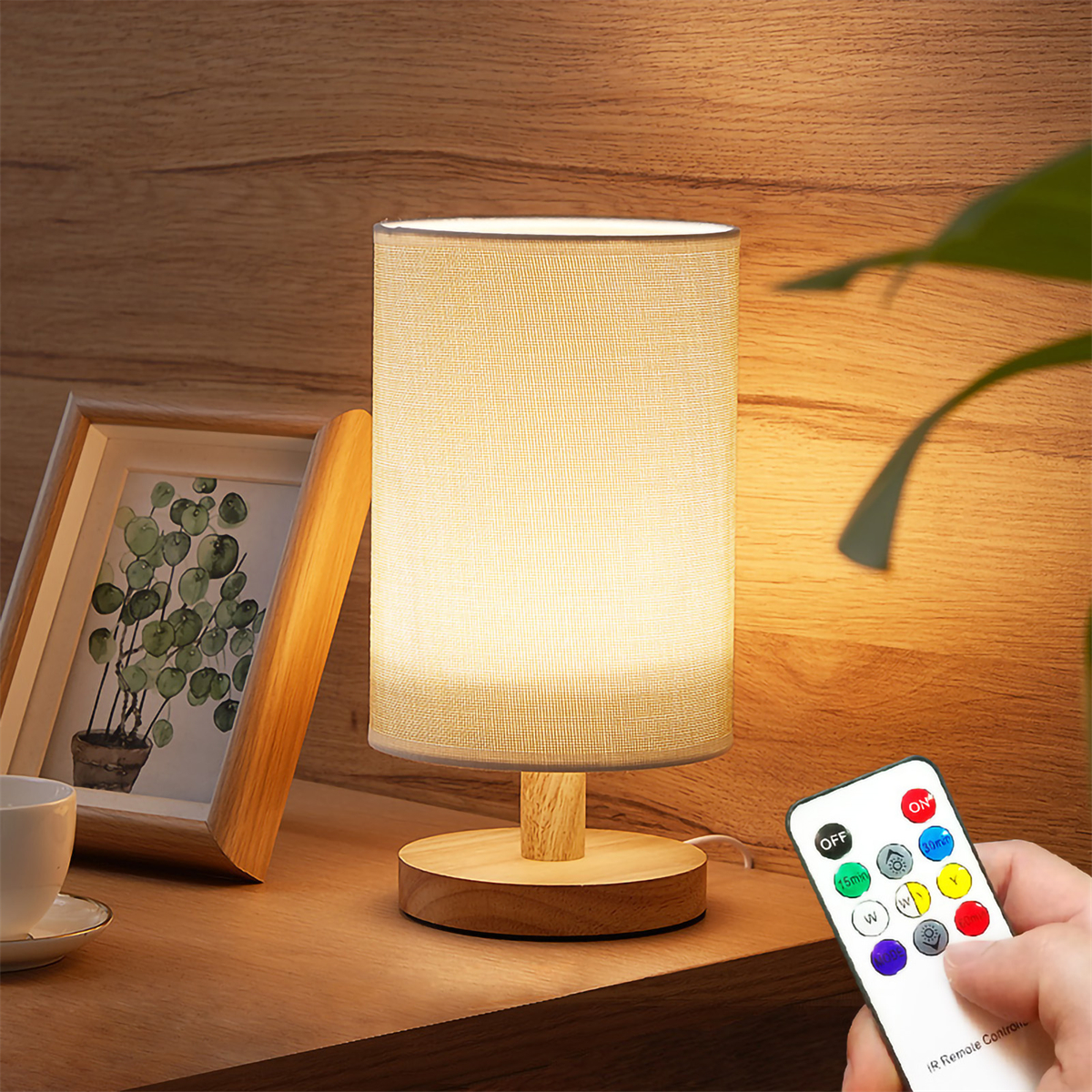 Tischlampe auf Holzoberfläche. Eine Fernbedienung in der Hand.