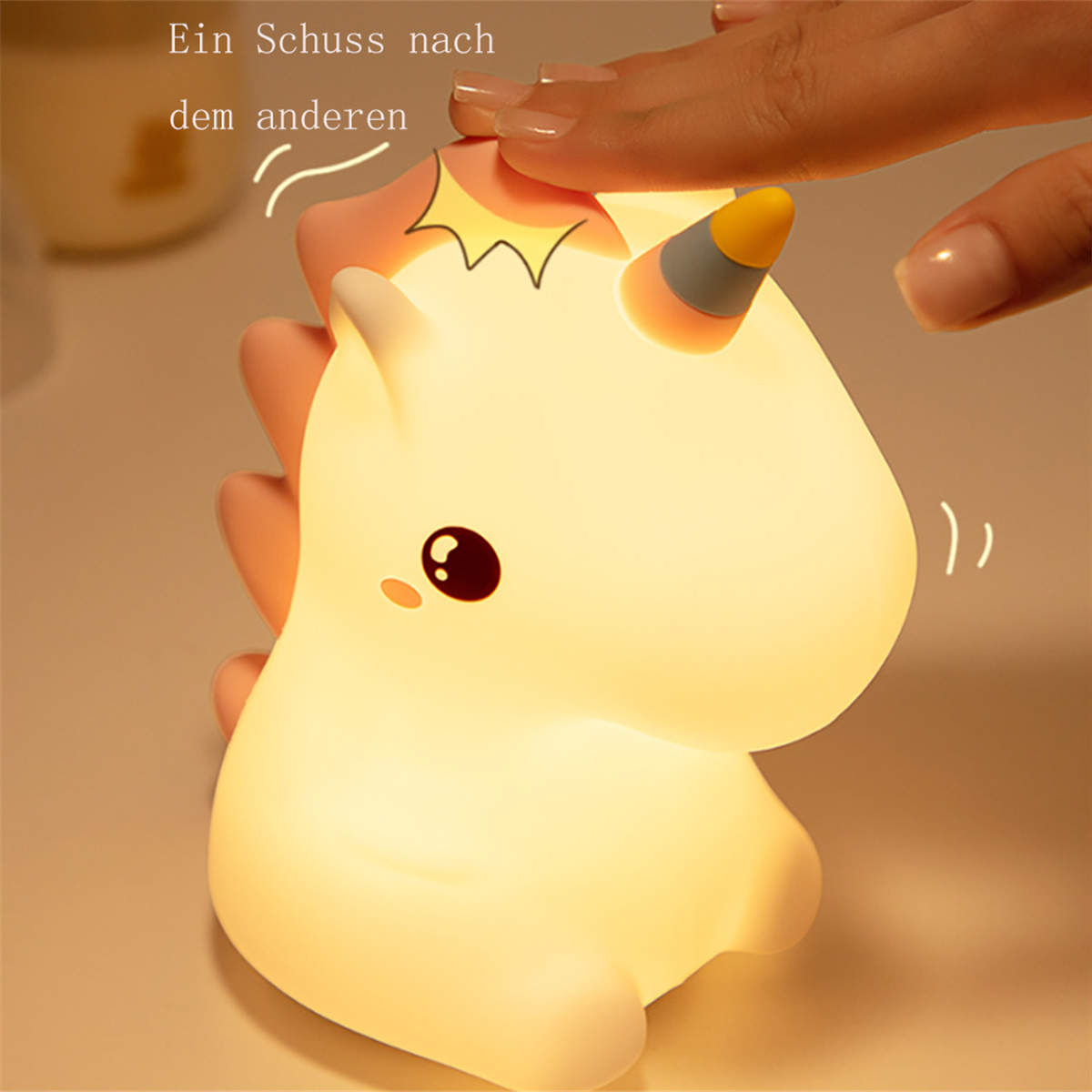 Eine leuchtende Einhorn-Lampe, die von einer Hand berührt wird. Das Licht ist warm und der Hintergrund verschwommen.