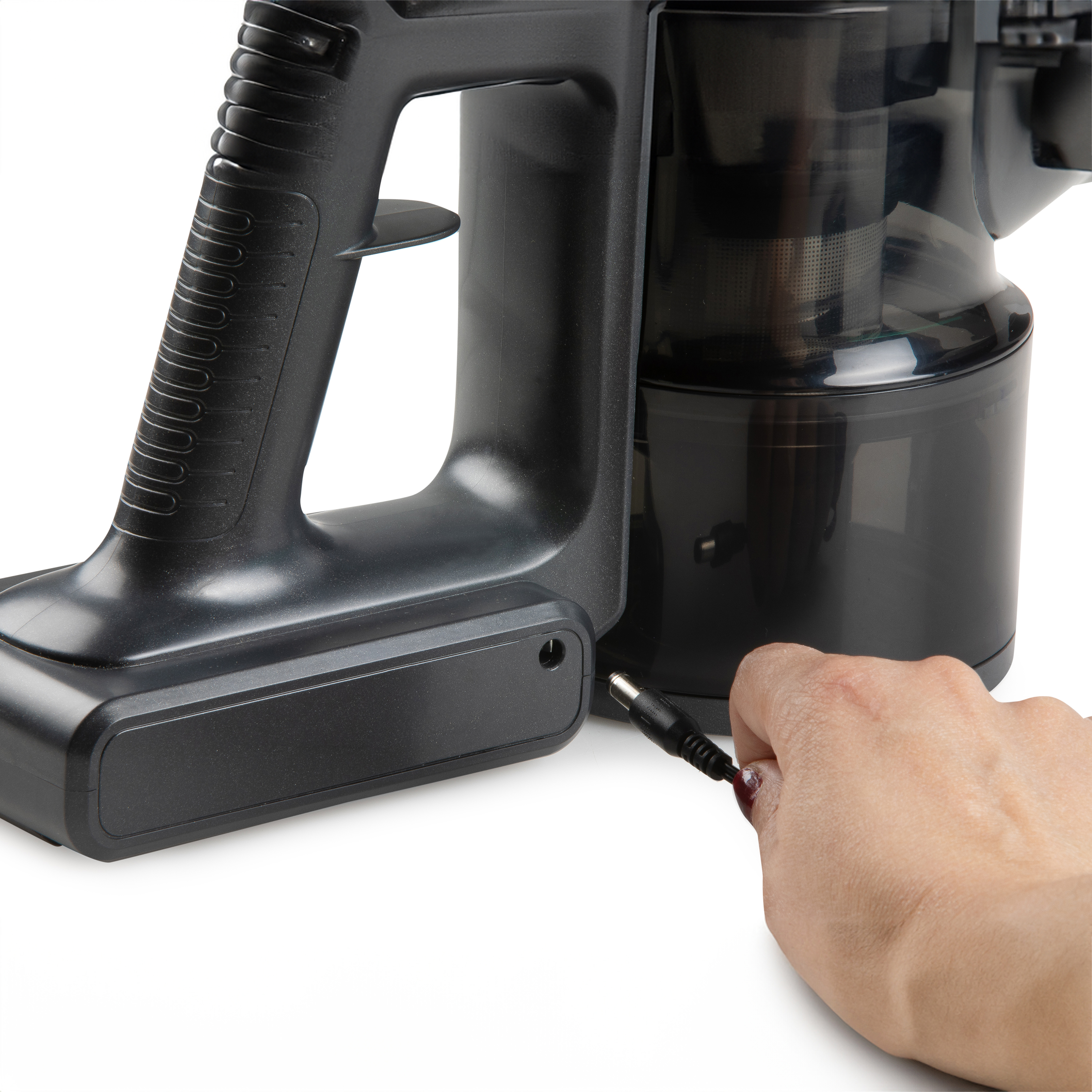 Close-up of a cordless vacuum cleaner with the charging port and hand plugging in the charger.