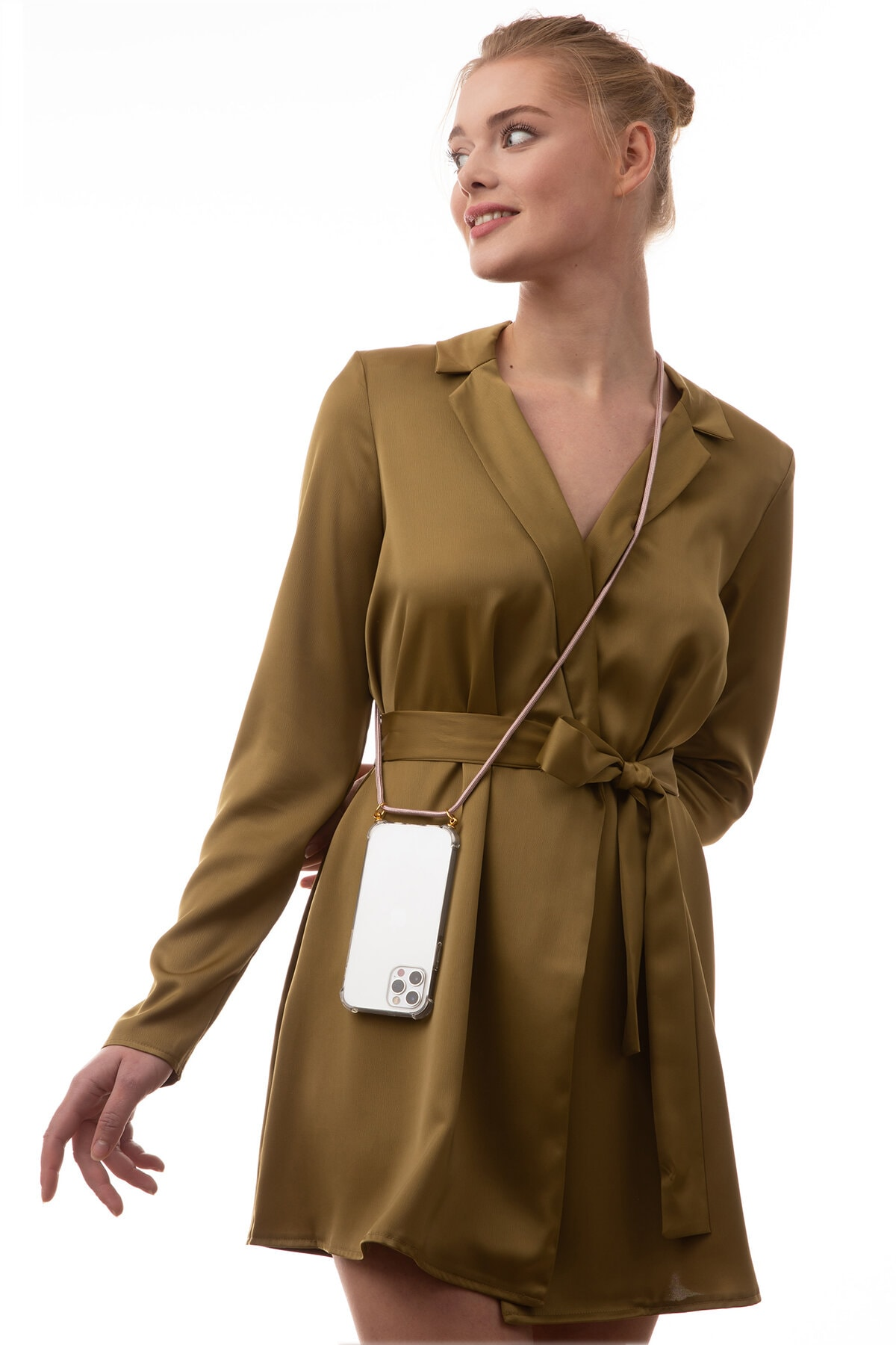 Frau in einem senffarbenen Kleid, hält ein Telefon an einem Riemen.