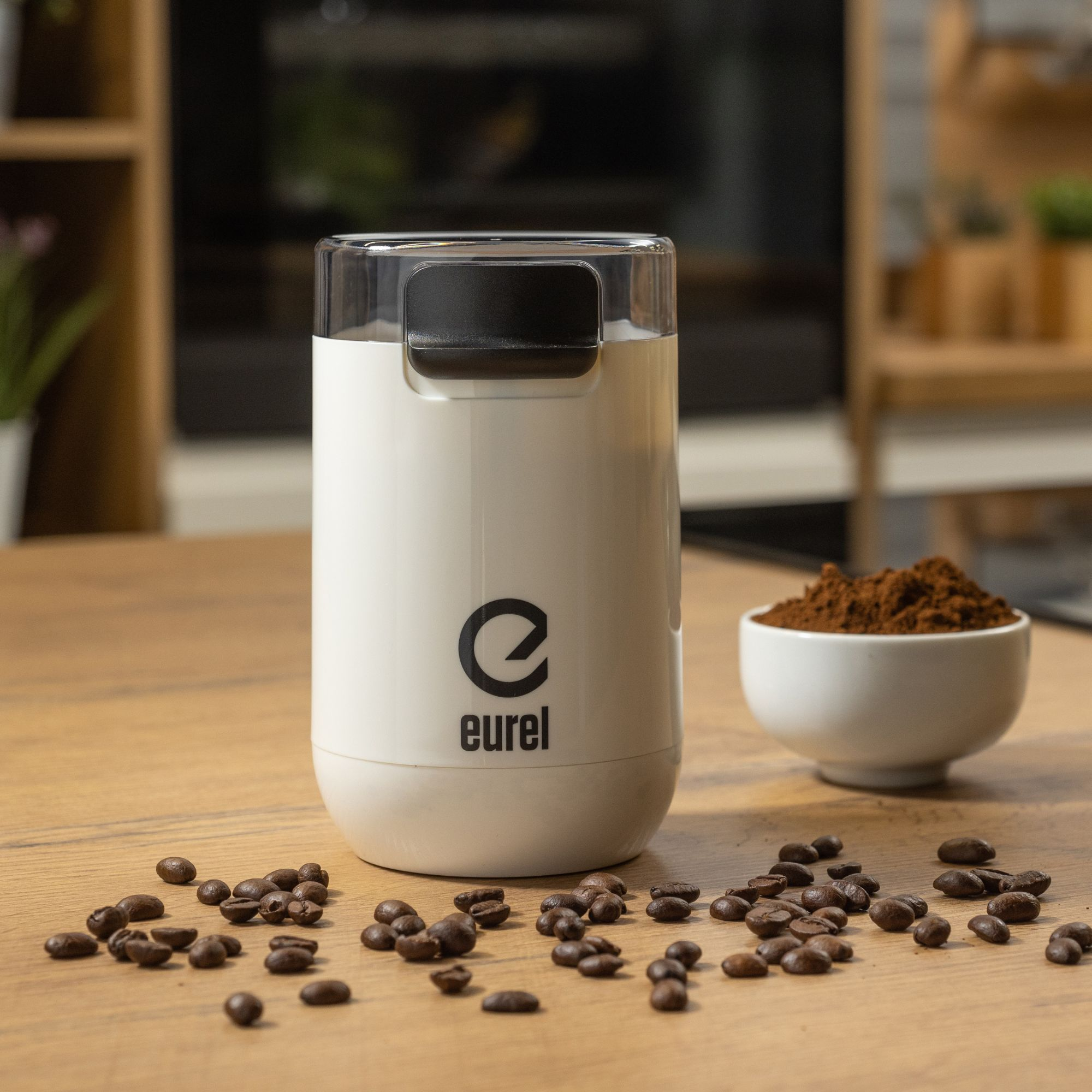 Weißer Kaffeemühle mit Kaffeebohnen und gemahlenem Kaffee auf Holztisch.