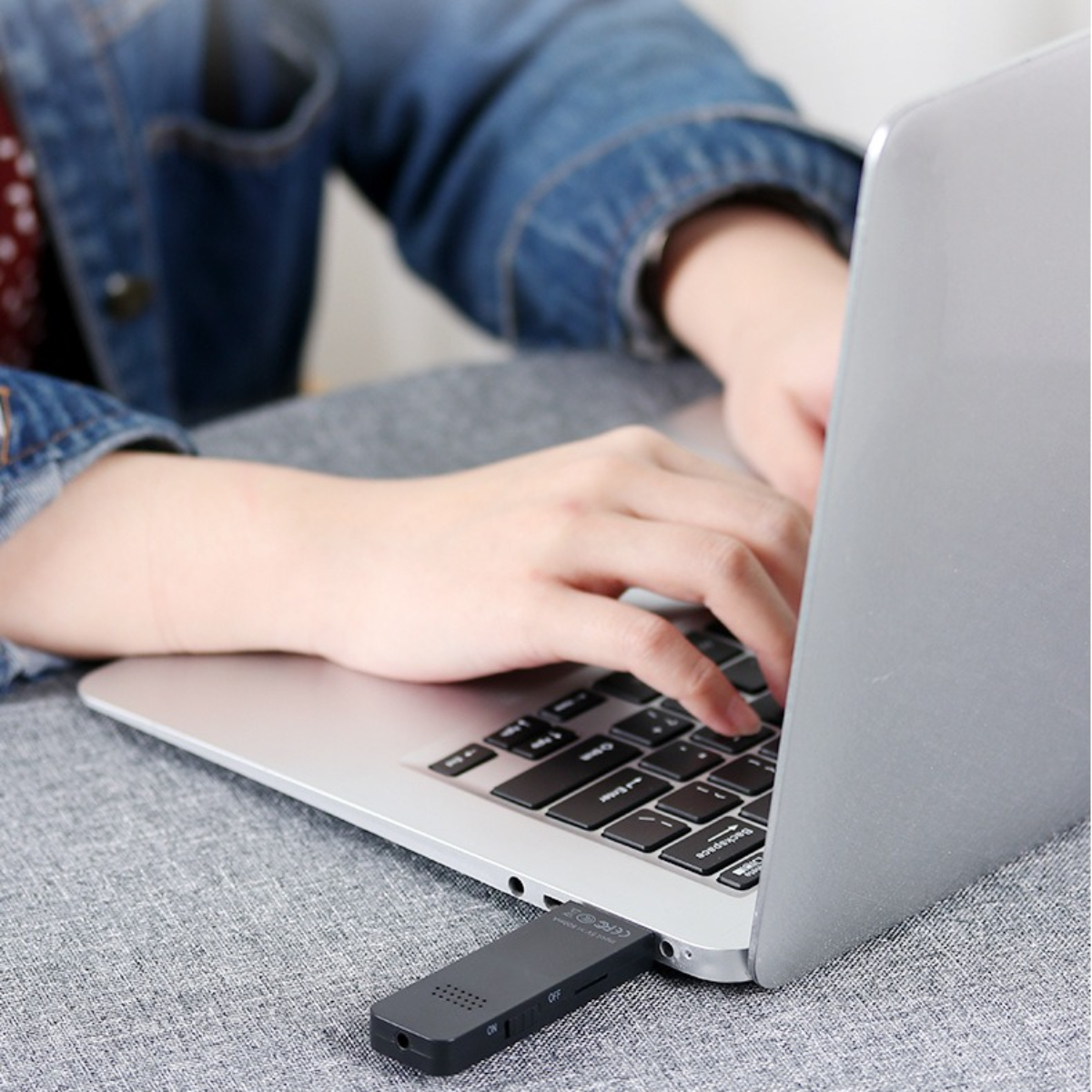Person, die einen Laptop benutzt, mit eingestecktem USB-Empfänger.