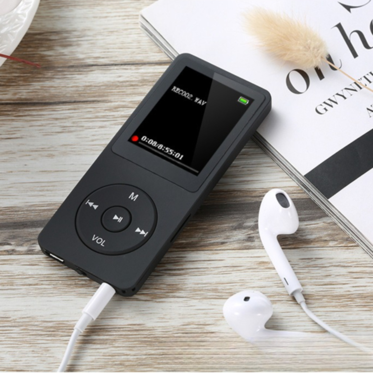 Schwarzer MP3-Player mit Bildschirm und Knöpfen. Weiße Kopfhörer liegen daneben. Holziger Hintergrund.
