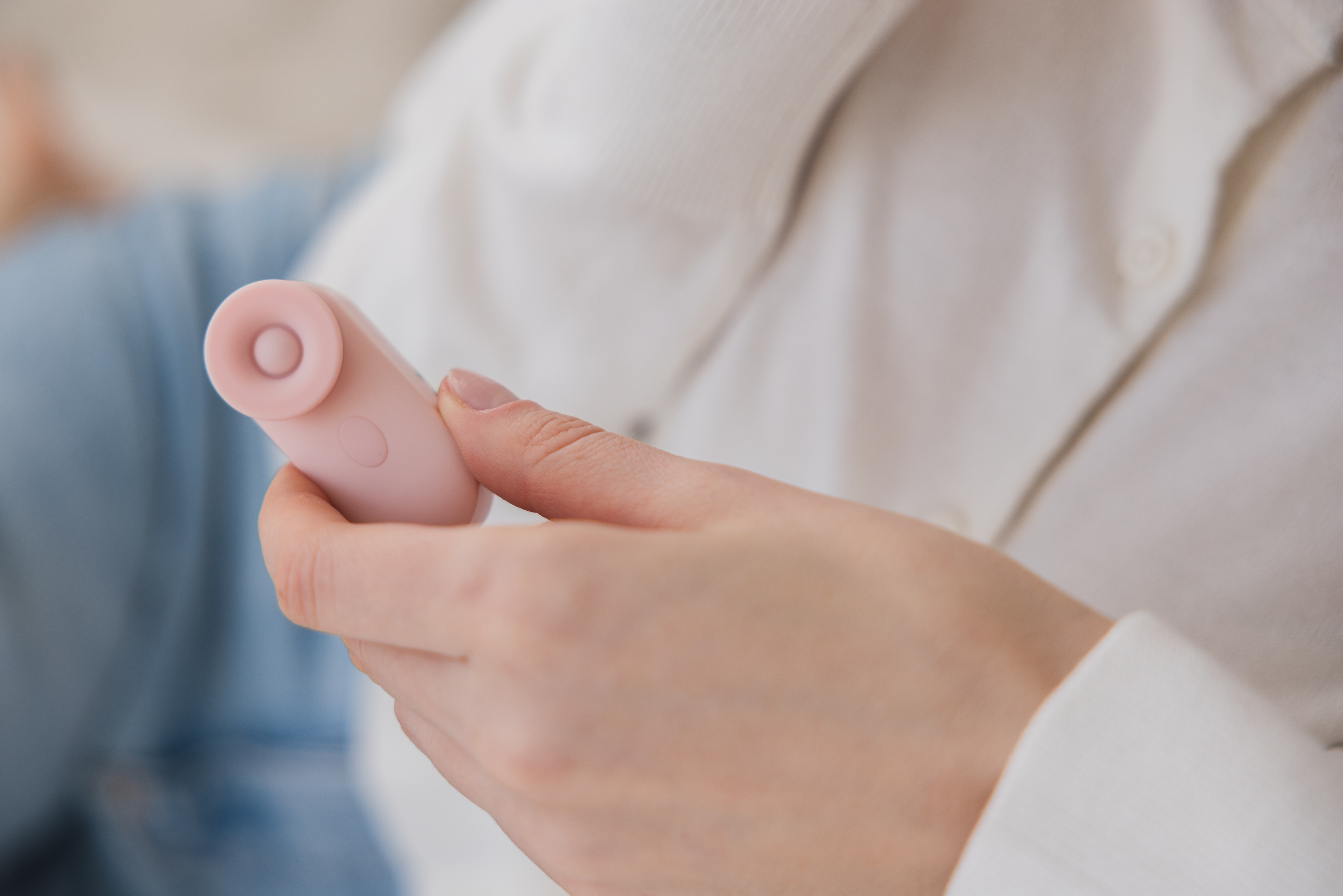 Eine Person hält ein pinkfarbenes, abgerundetes Sexspielzeug mit einem kleinen, kreisförmigen Kopf.