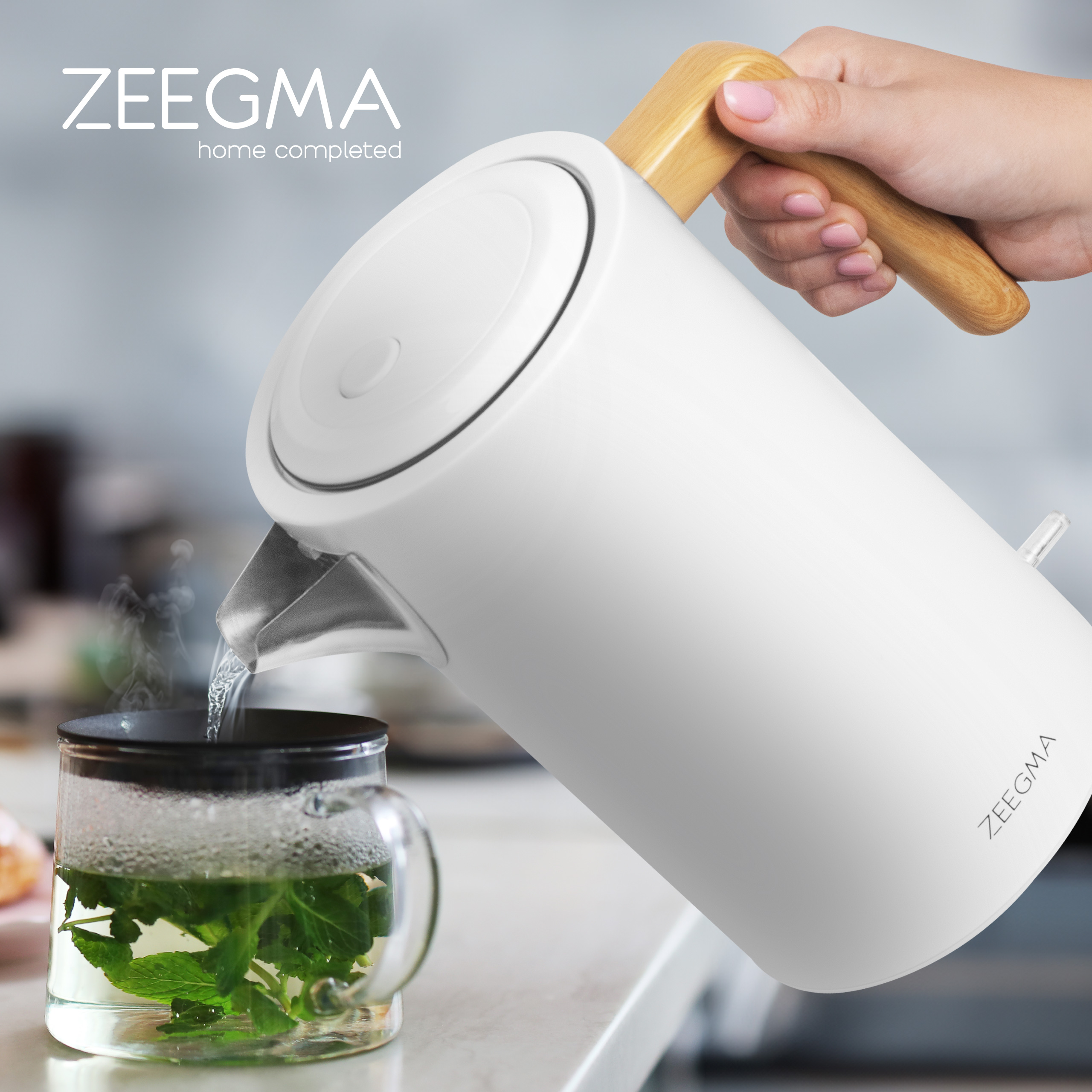 Biały czajnik elektryczny wlewa wodę do szklanki z miętą.