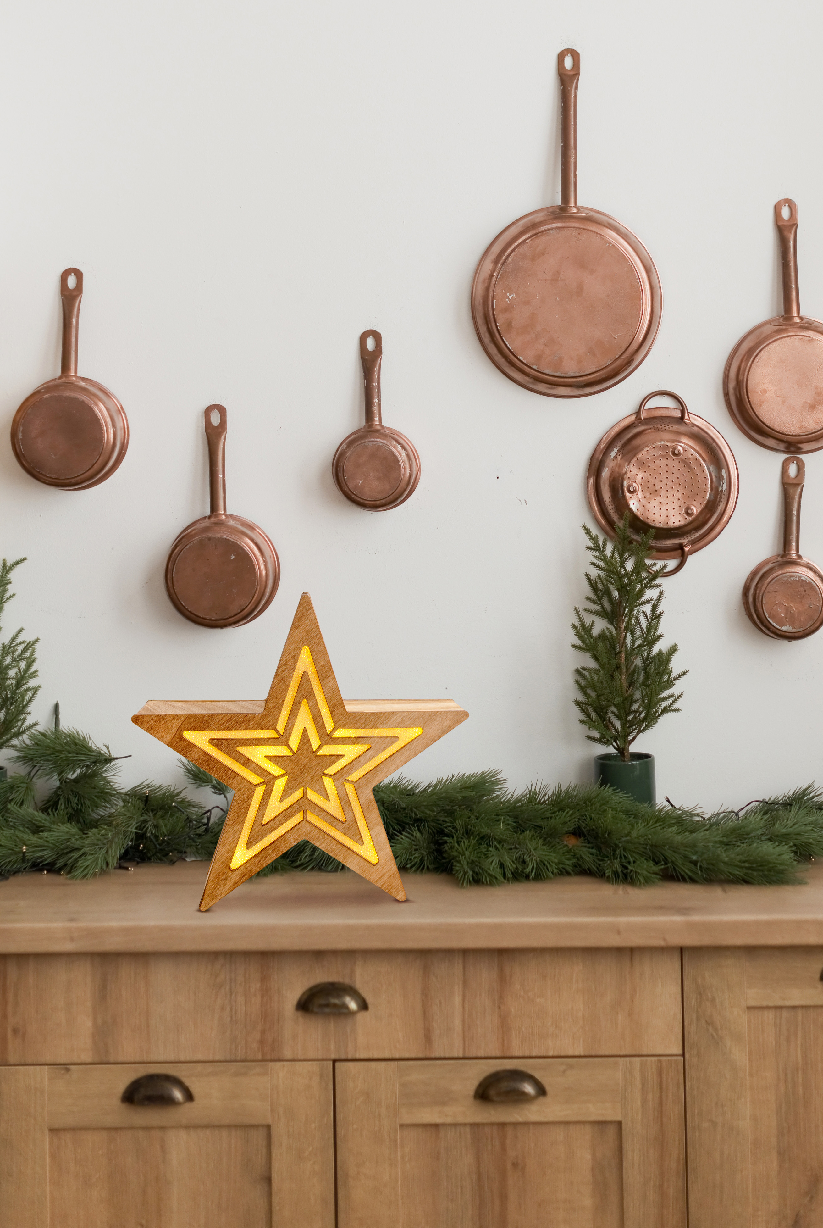 Hölzerne Stern Dekoration auf einem Holztisch, Kupferpfannen an der Wand.