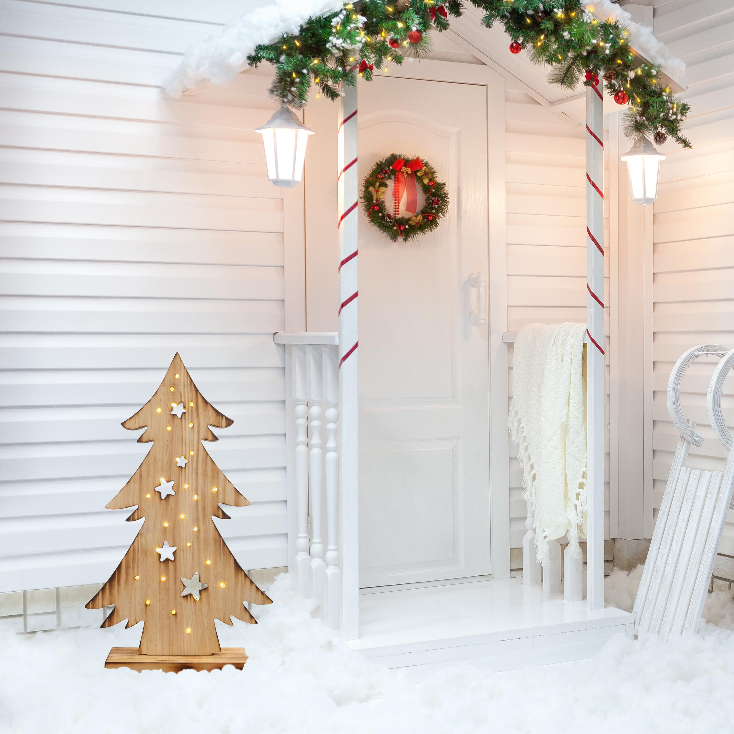 Eine Weihnachtsszene mit einem Baum aus Holz und einem weißen Eingang mit Lichtern und Schnee.