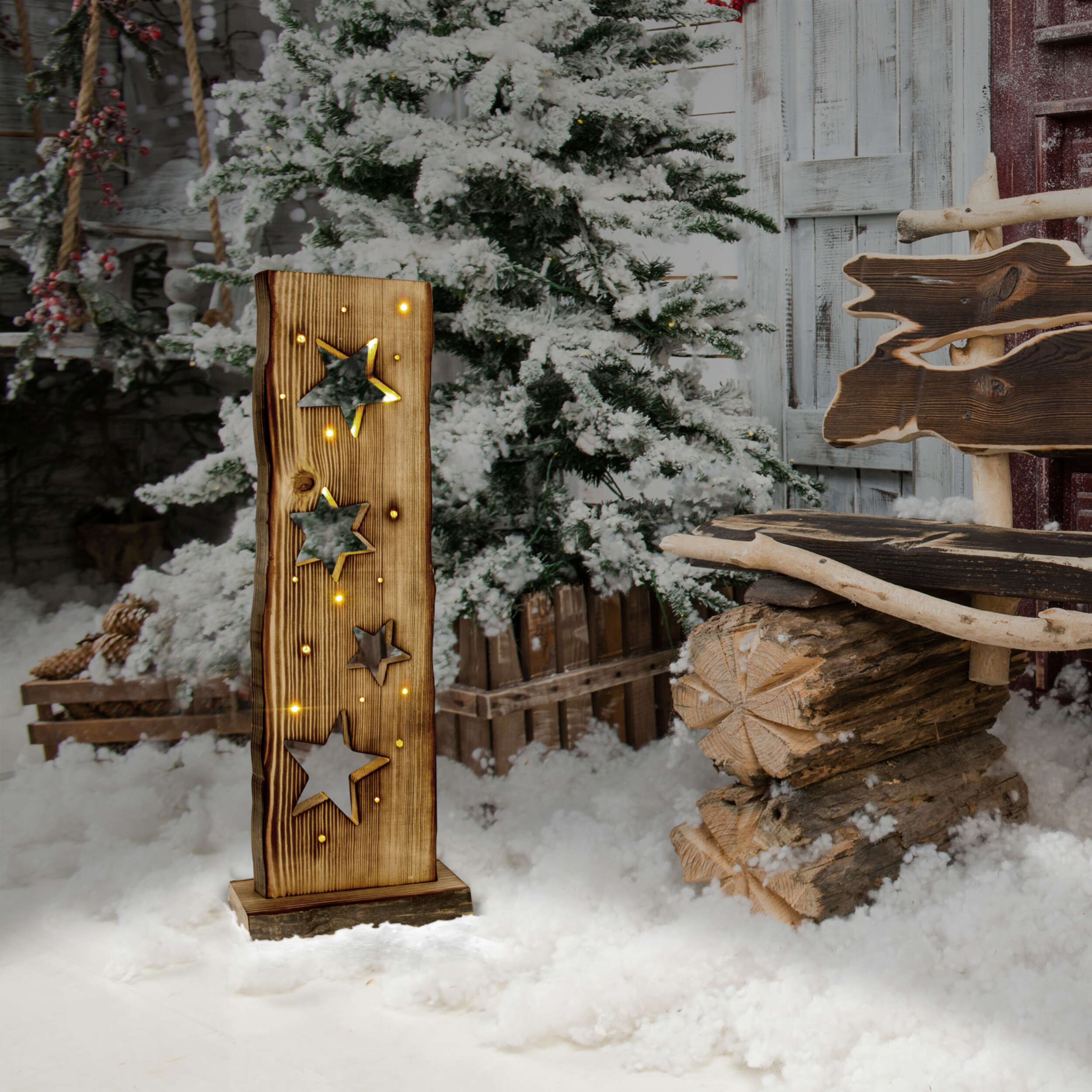 Weihnachtsdekoration aus Holz mit Sternen und Lichtern in einer verschneiten Winterszene.