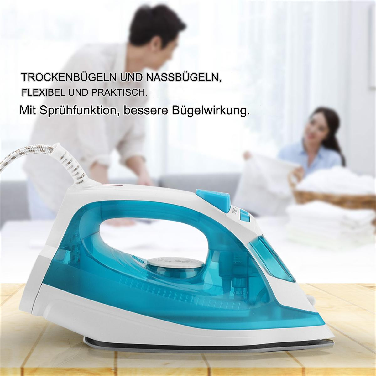 Weißes und teal-farbenes Bügeleisen auf einer Holzoberfläche. Im Hintergrund faltet ein Paar Kleidung.