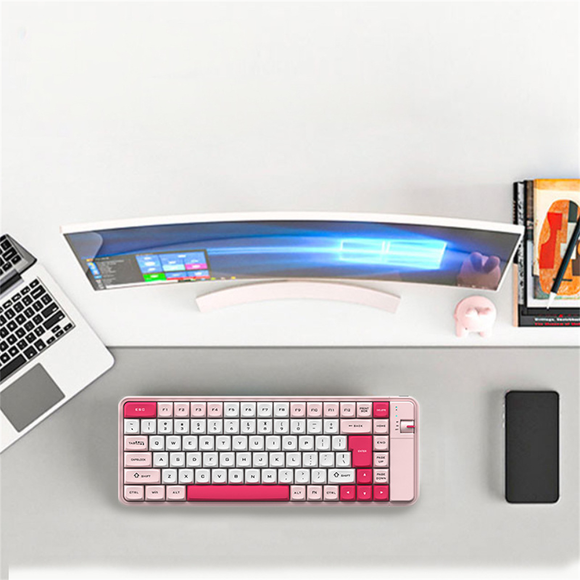 Rosa Tastatur, Monitor, Maus und Telefon auf einem grauen Schreibtisch.