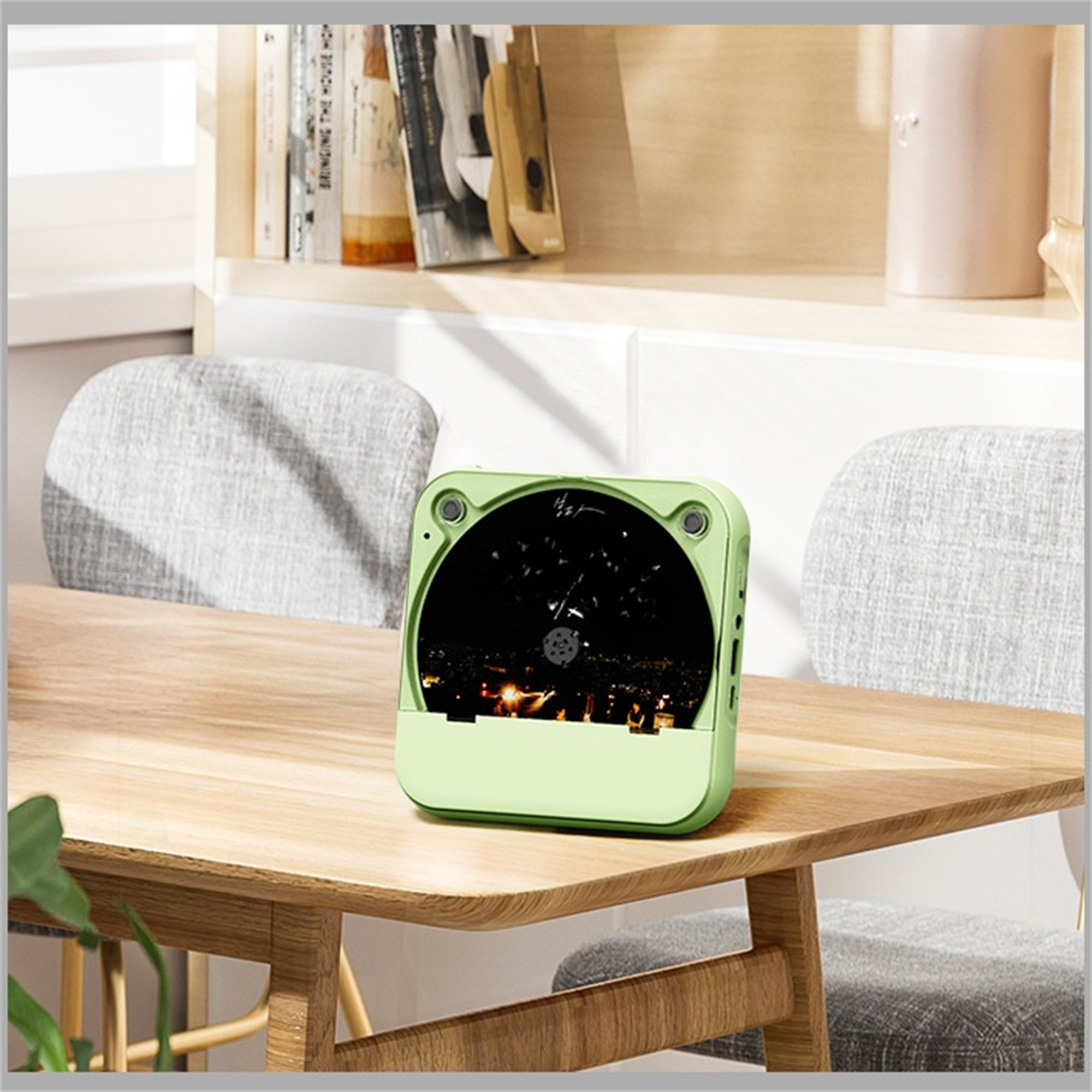 Ein grünes Gerät mit Linse und Knöpfen liegt auf einem Holztisch mit verschwommenem Hintergrund.