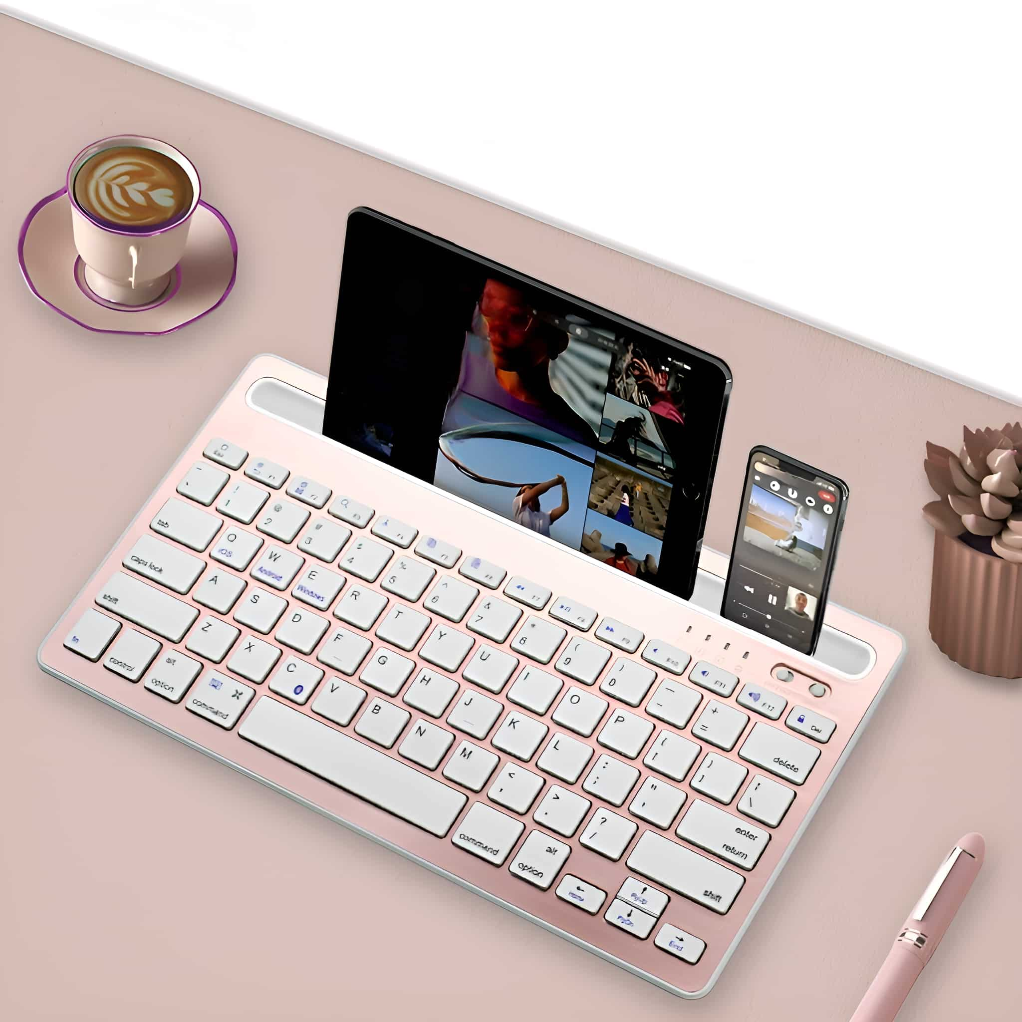 Eine rosa Tastatur, ein Tablet, ein Telefon, ein rosa Stift und eine Tasse Kaffee.