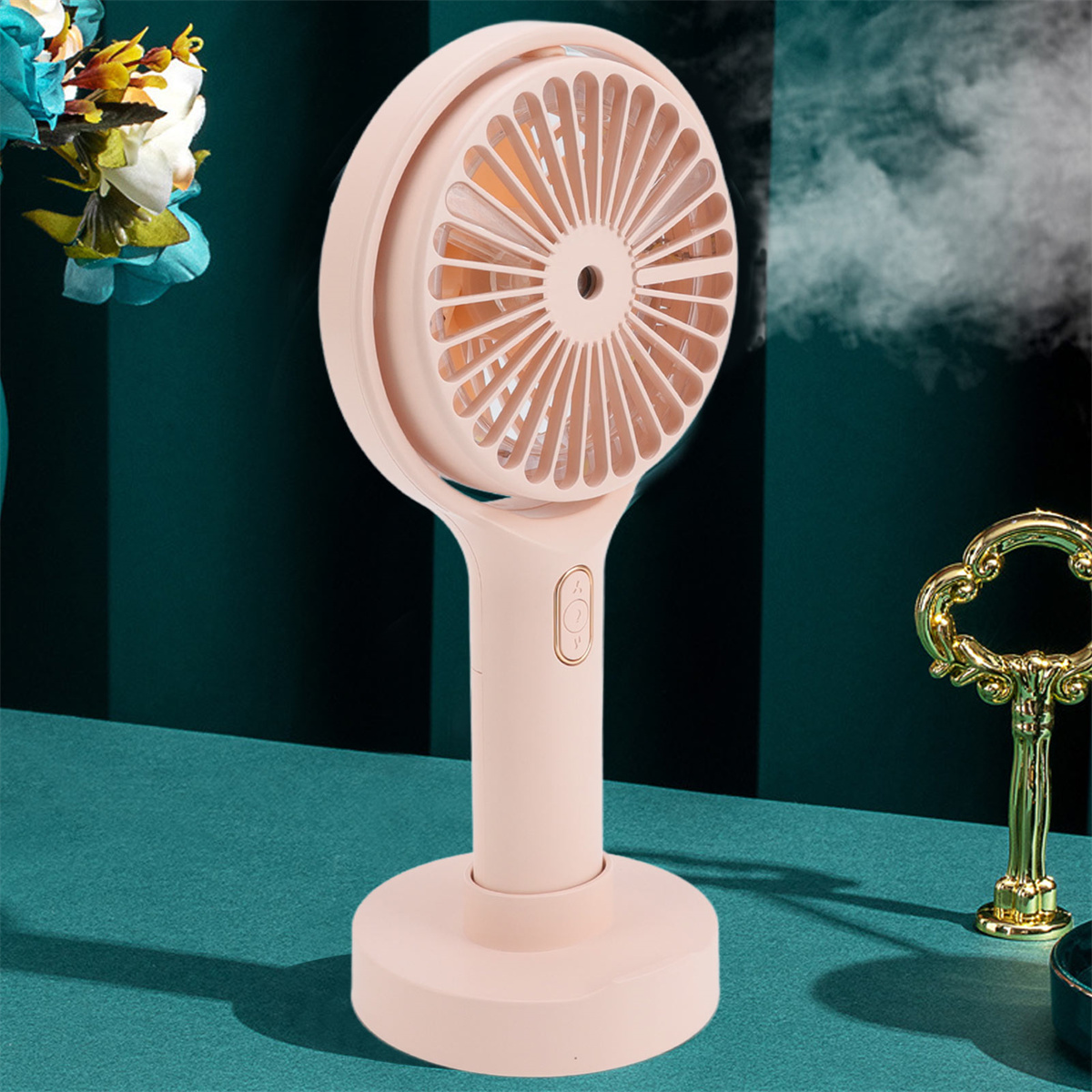 Rosa tragbarer Ventilator mit Ständer, auf blauer Oberfläche. Goldener Schlüssel und Blumen im Hintergrund.