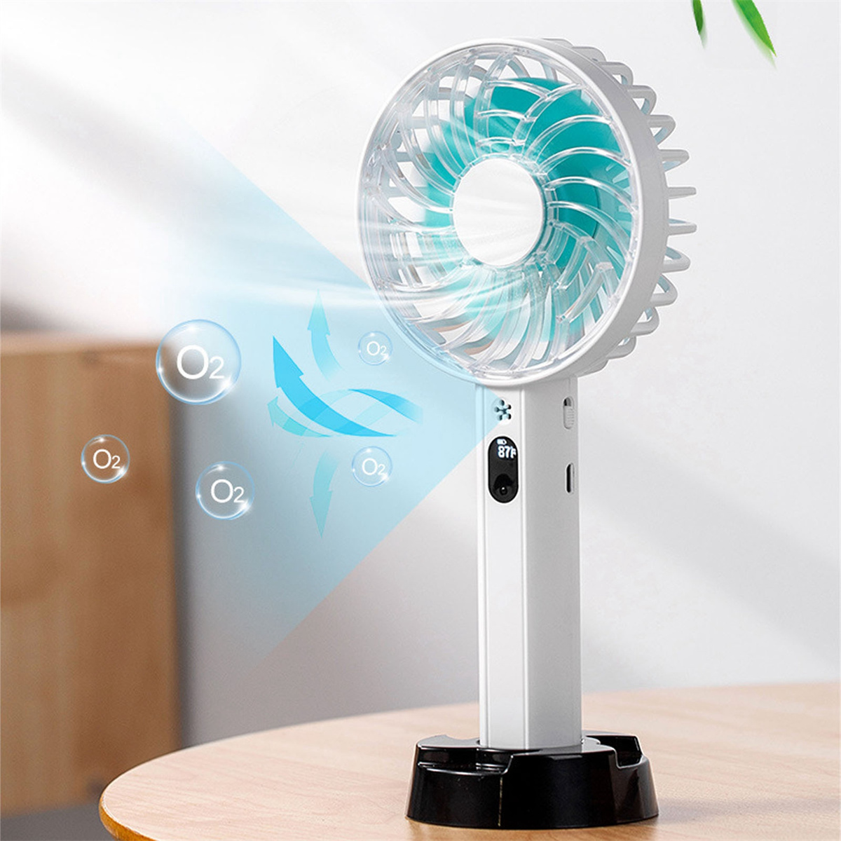 Weißer und türkisfarbener Handventilator auf einem Tisch. Sauerstoffblasen schweben. Der Hintergrund ist eine weiße Wand.