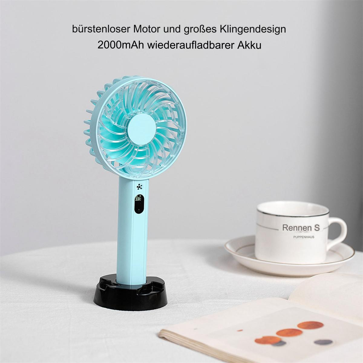 Ein handgehaltener türkisfarbener Ventilator mit schwarzem Sockel, daneben eine Tasse und ein Buch.