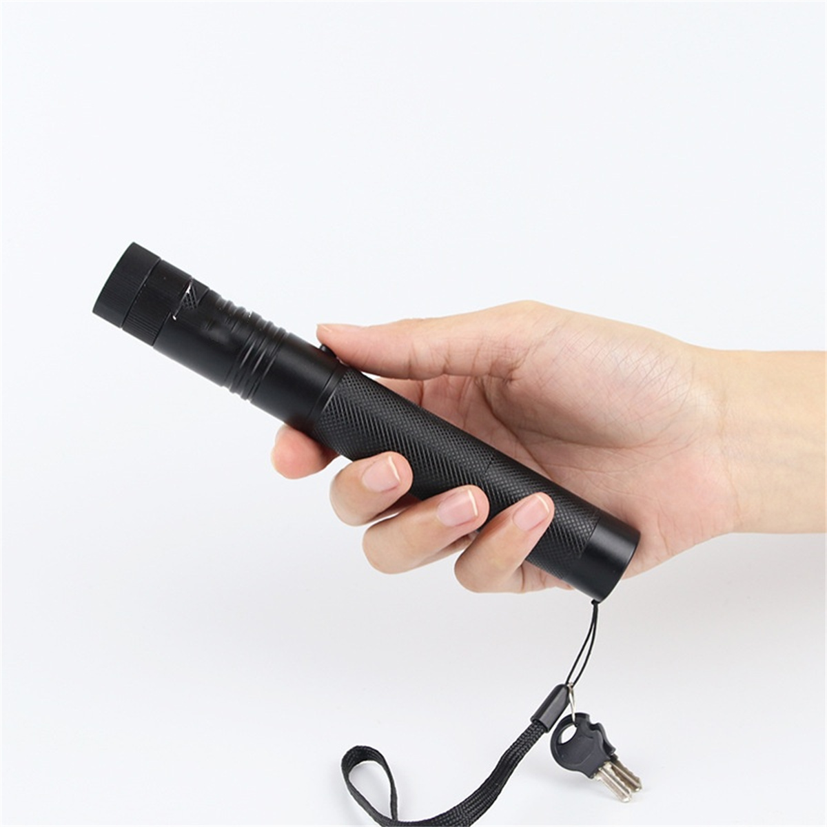 Eine schwarze Taschenlampe in einer Hand gehalten, mit einem Schlüssel befestigt.